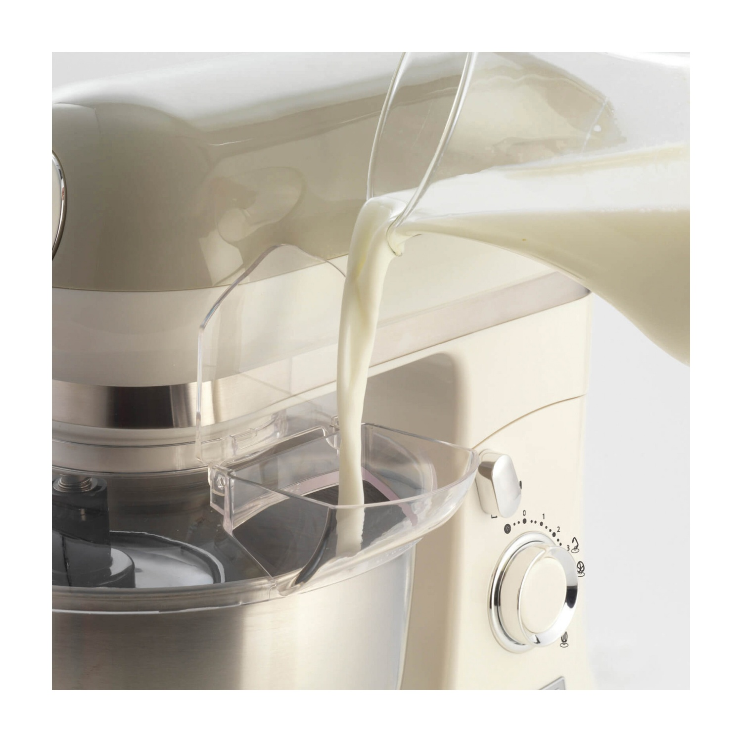 Un mixer con latte che ci versa dentro. Colore beige. Sfondo bianco.