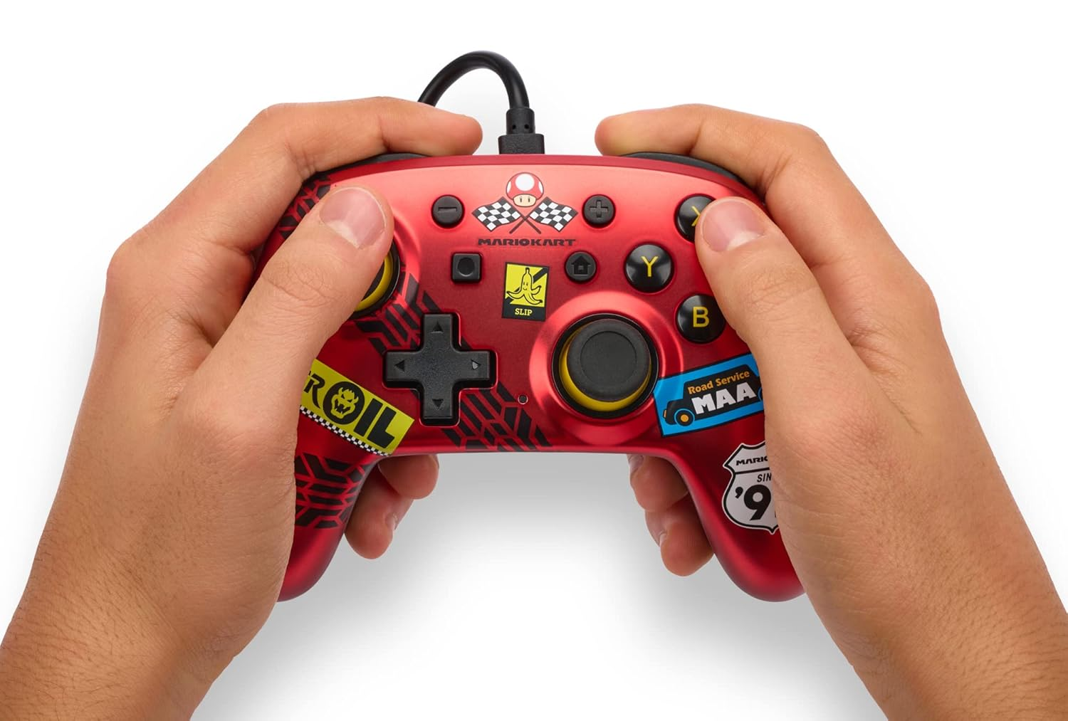 Eller, çeşitli çıkartmalarla kırmızı bir Mario Kart Switch denetleyicisi tutuyor.