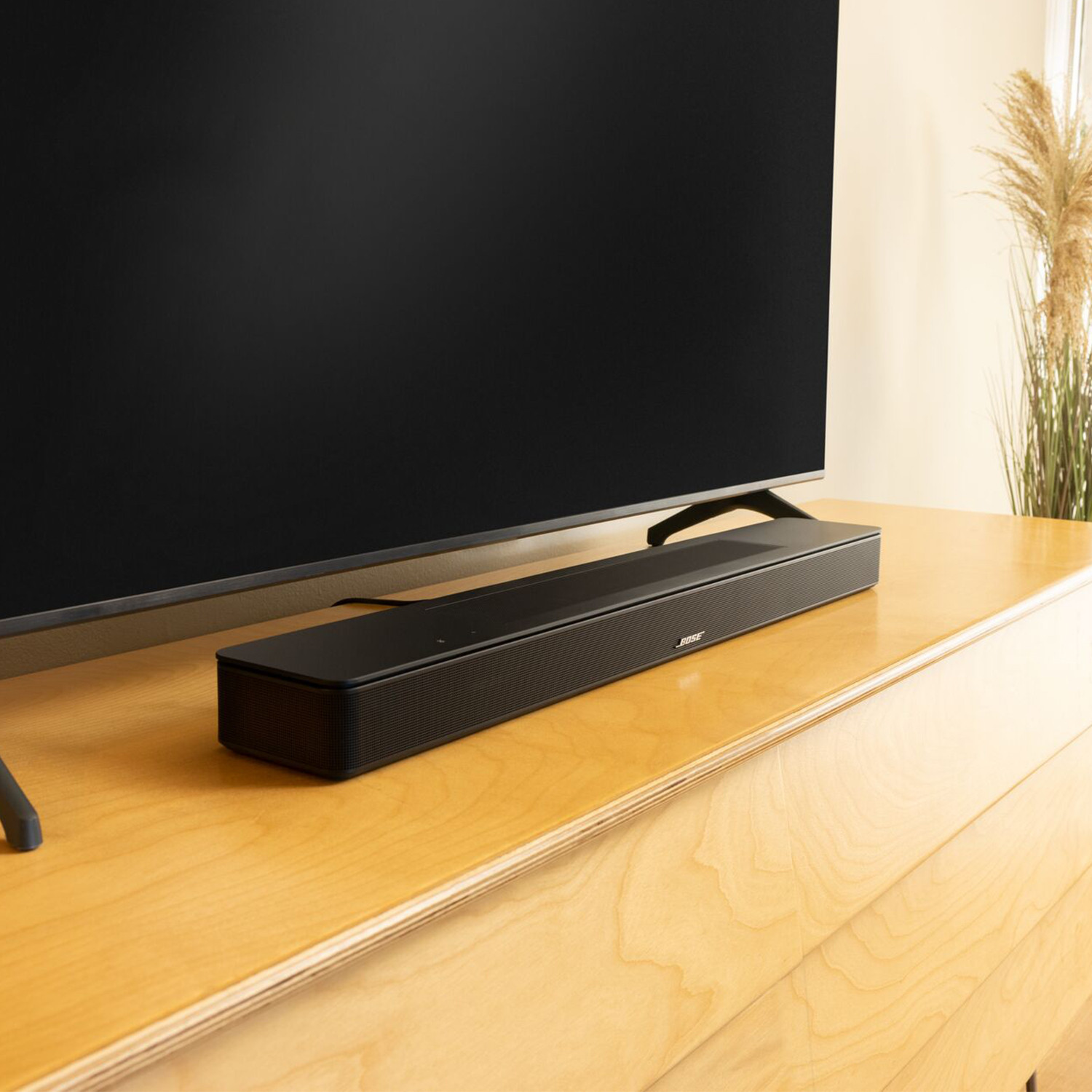 Fekete soundbar a TV alatt egy fa szekrényen.