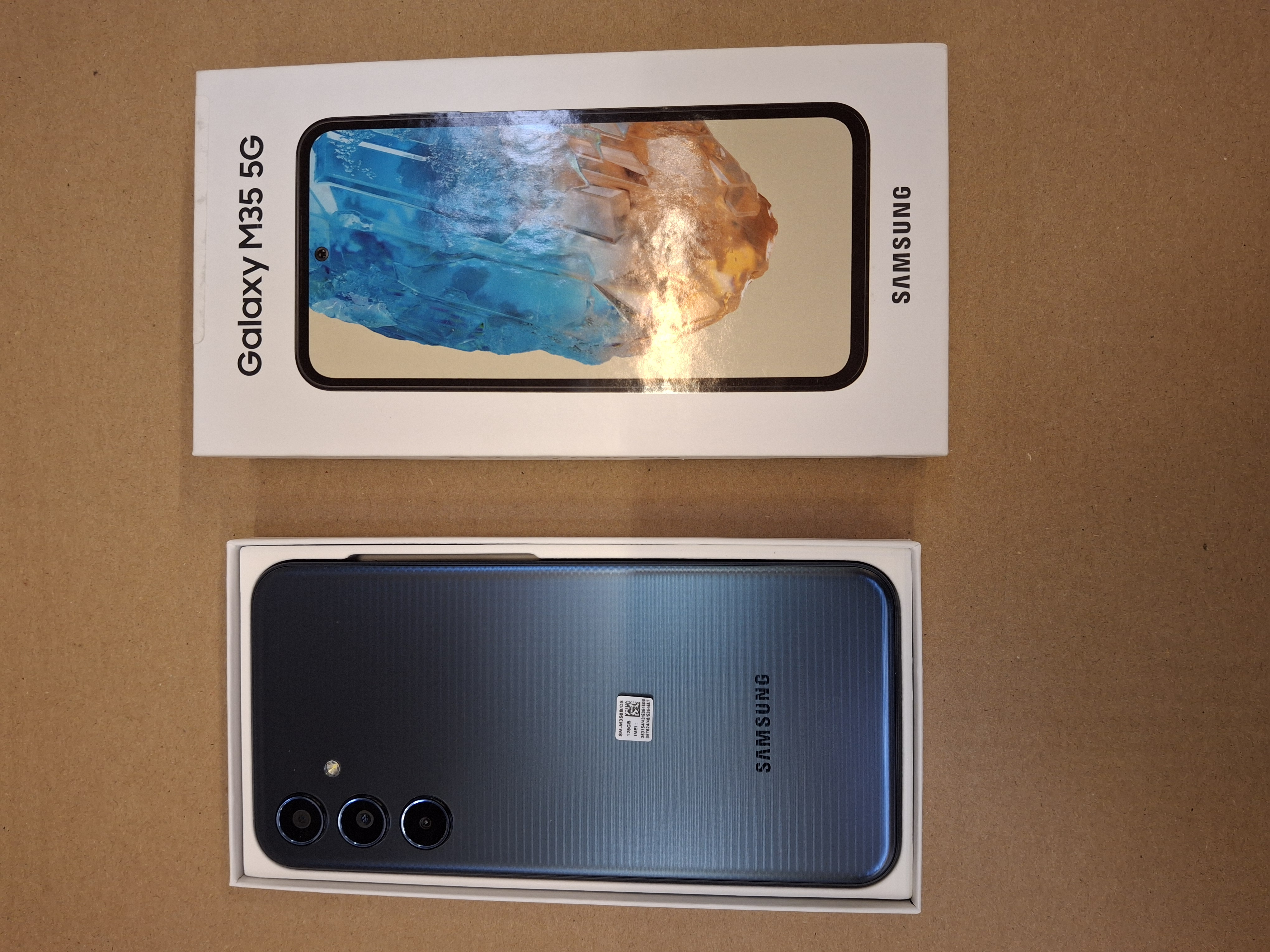 Smartfon w pudełku i telefon na powierzchni.