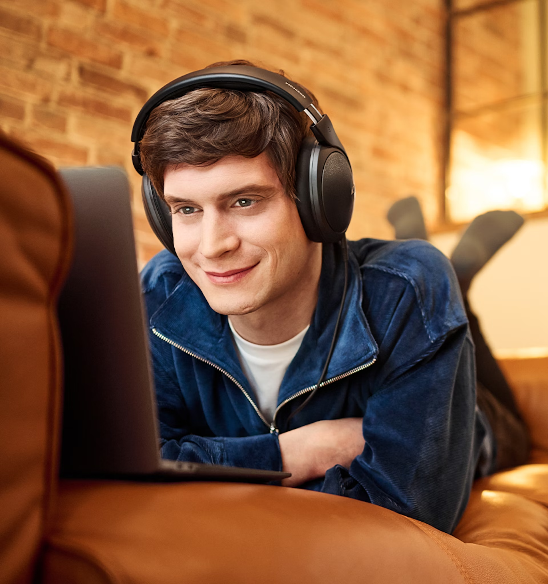 Mann mit Kopfhörern, der auf einen Laptop blickt.