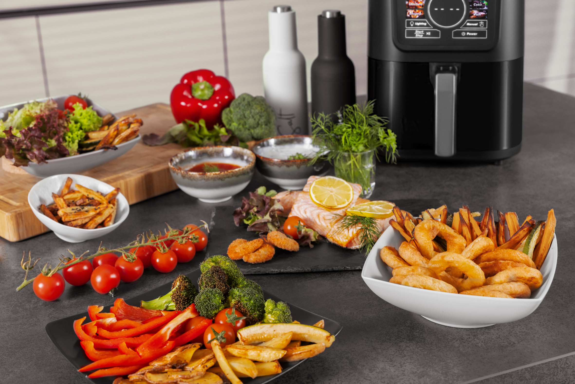 Speisenanordnung: Heißluftfritteuse, Gemüse, Pommes, Lachs und mehr. Eine kulinarische Szene.