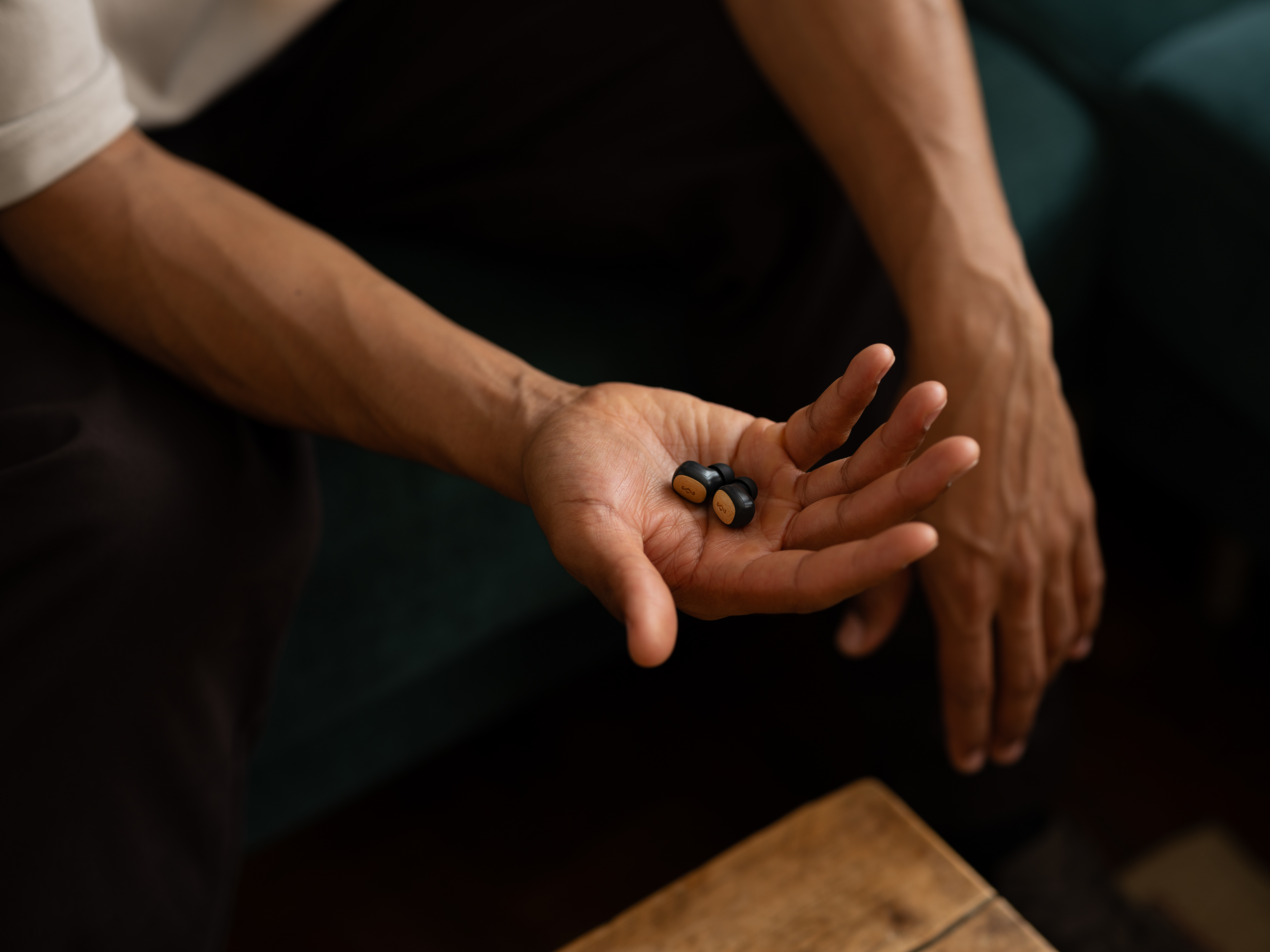 Eine Hand, die zwei schwarze Ohrhörer hält.