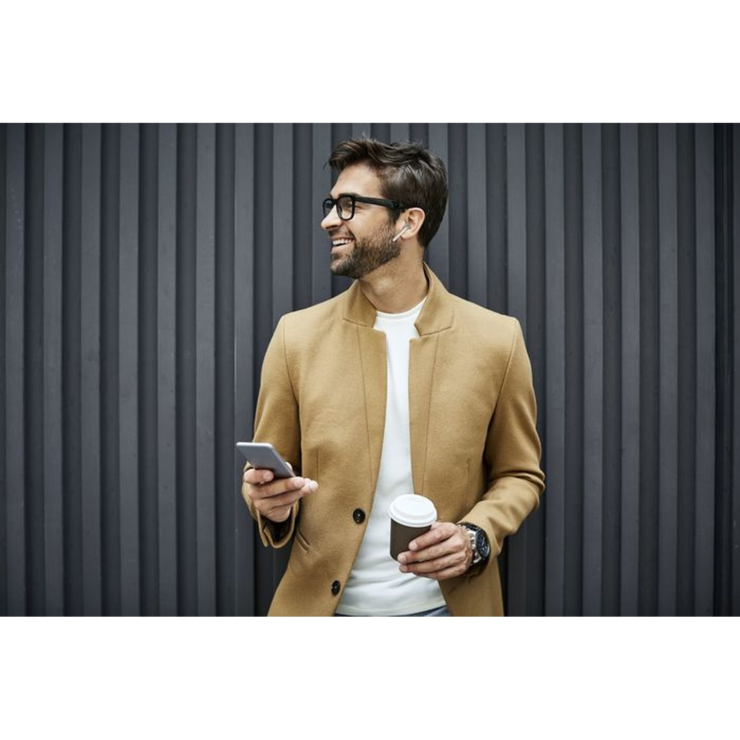 Uomo con caffè e telefono. Uomo con occhiali, cappotto, tiene telefono e tazza di caffè, sfondo grigio.