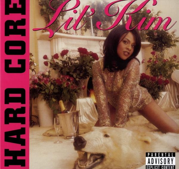 Album borító: Lil' Kim arany ruhában a szőnyegen. Rózsaszín szöveg: Hard Core és figyelmeztetés.