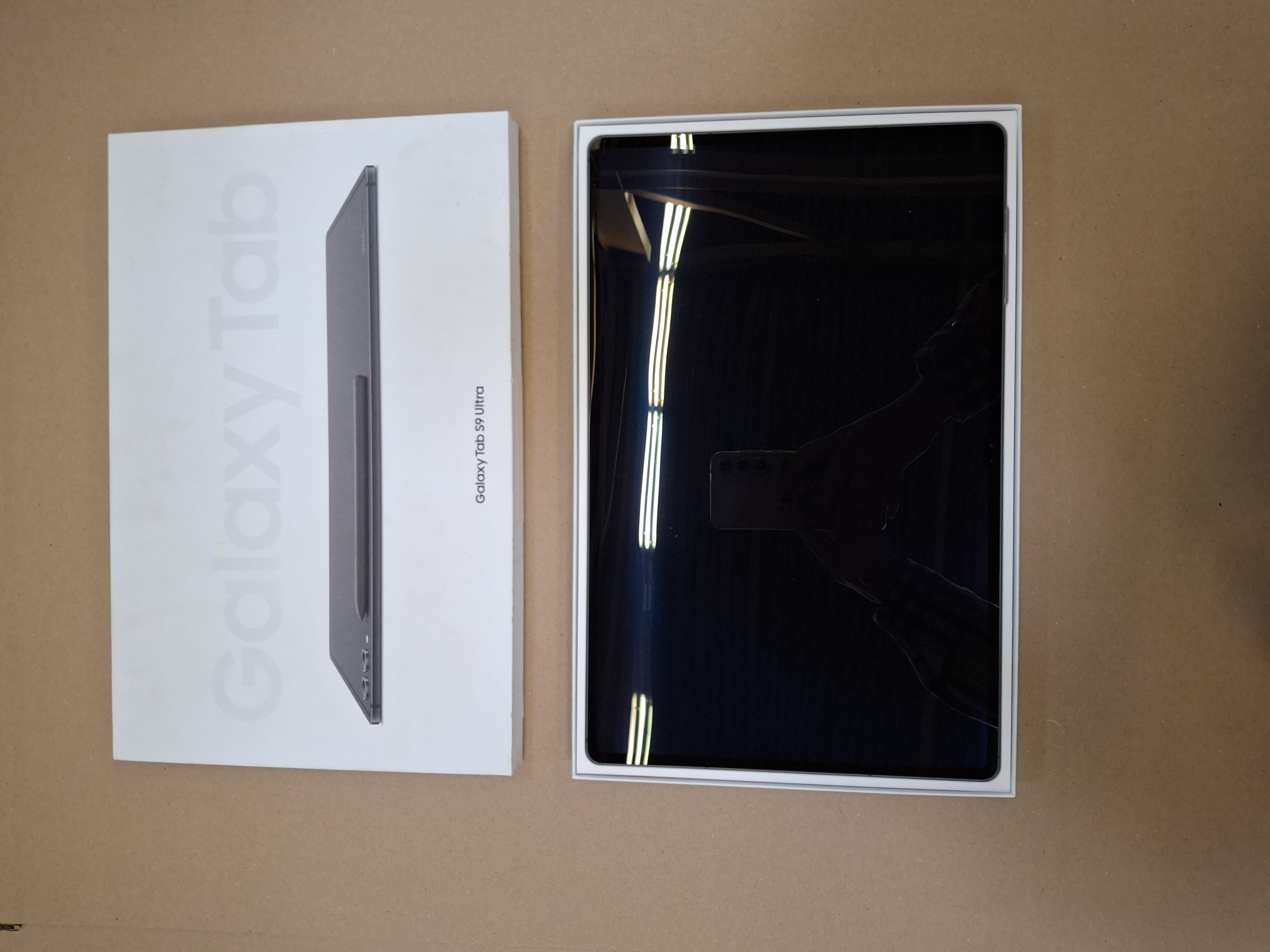 Tablet i jego pudełko. Tablet jest czarny, z etykietą Galaxy Tab S9 Ultra na pudełku.