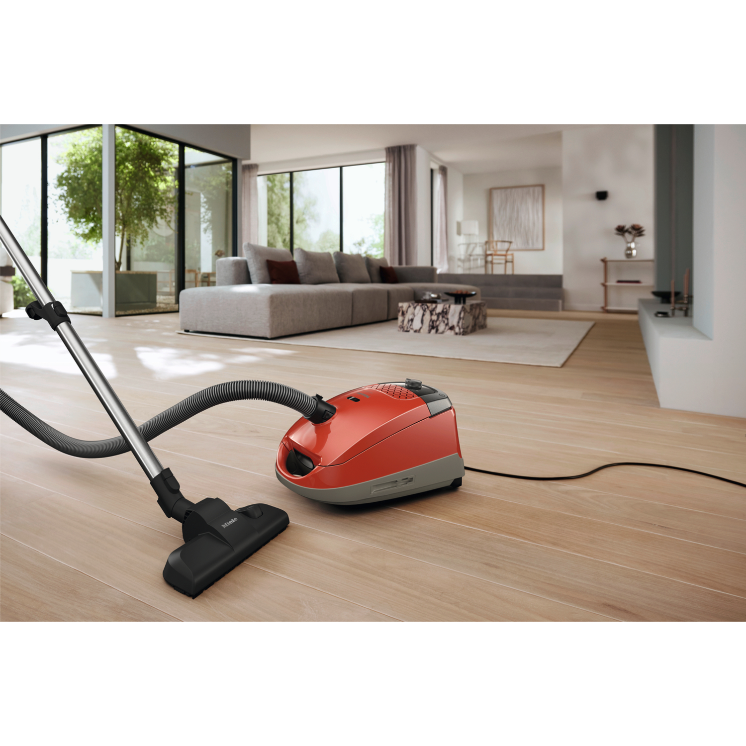 Een rode stofzuiger op een houten vloer. Een woonkamer op de achtergrond.