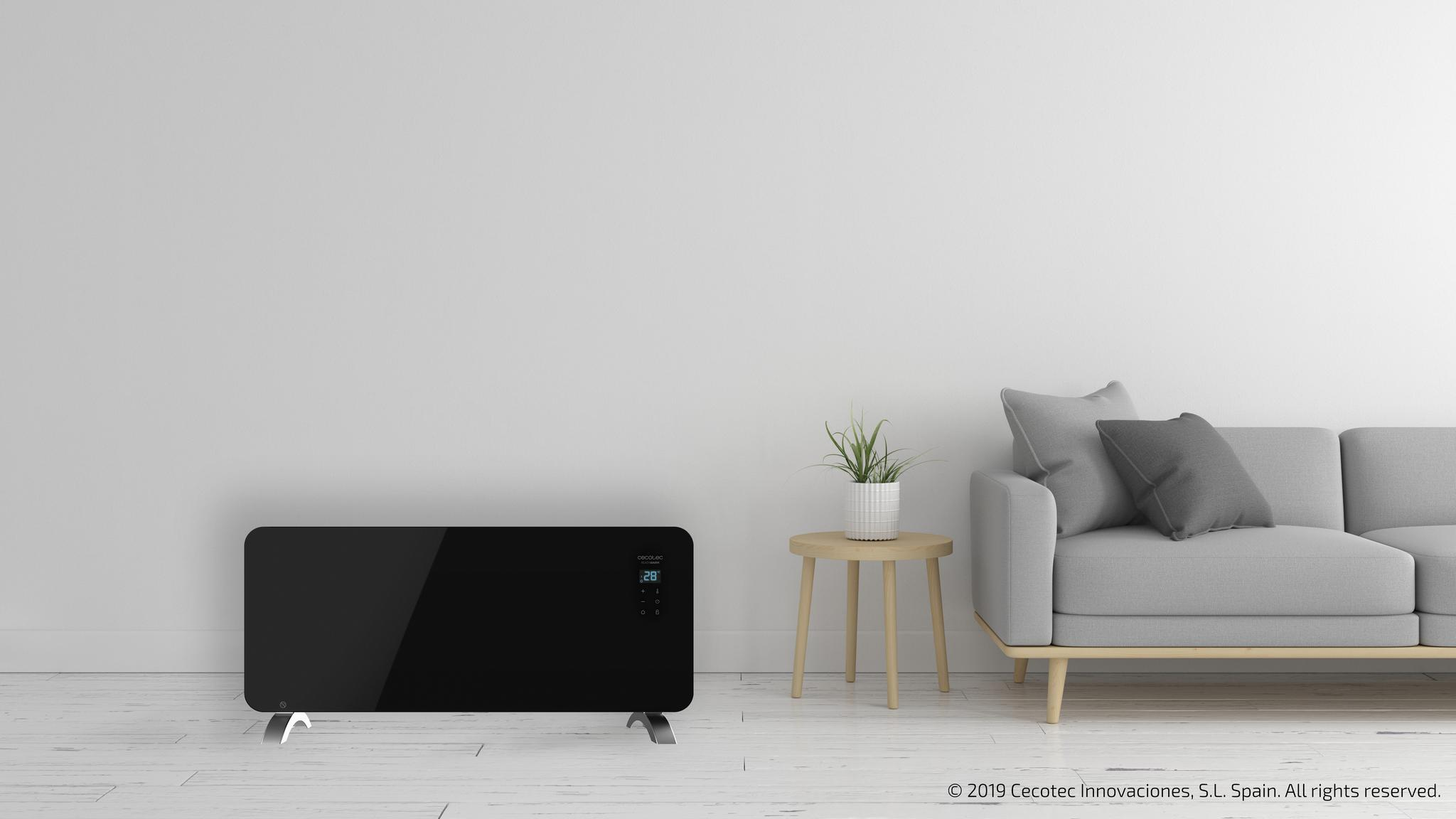 Calentador eléctrico negro con pantalla, junto a sofá y planta.
