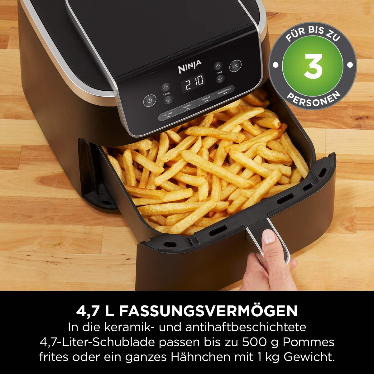 Friggitrice ad aria nera con patatine fritte. Una mano tiene il cassetto.