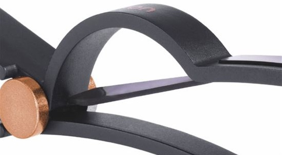 Zbliżenie czarnego metalowego przedmiotu z miedzianym okręgiem i cienkim, ciemnym ostrzem.