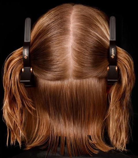 Włosy są przedzielone i spięte. Klipsy Dyson trzymają partie brązowych włosów.