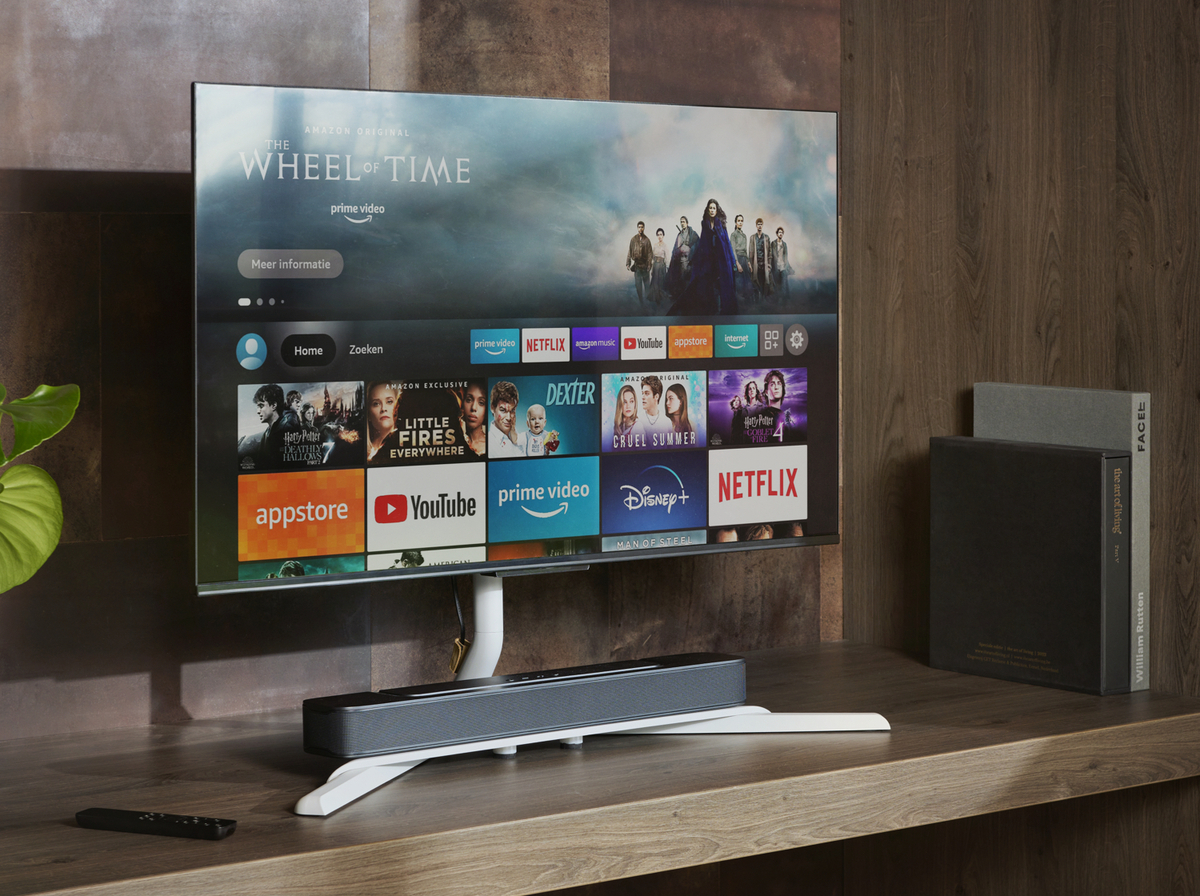 TV-Bildschirm mit Oberfläche, Soundbar und Fernbedienung auf Holz.