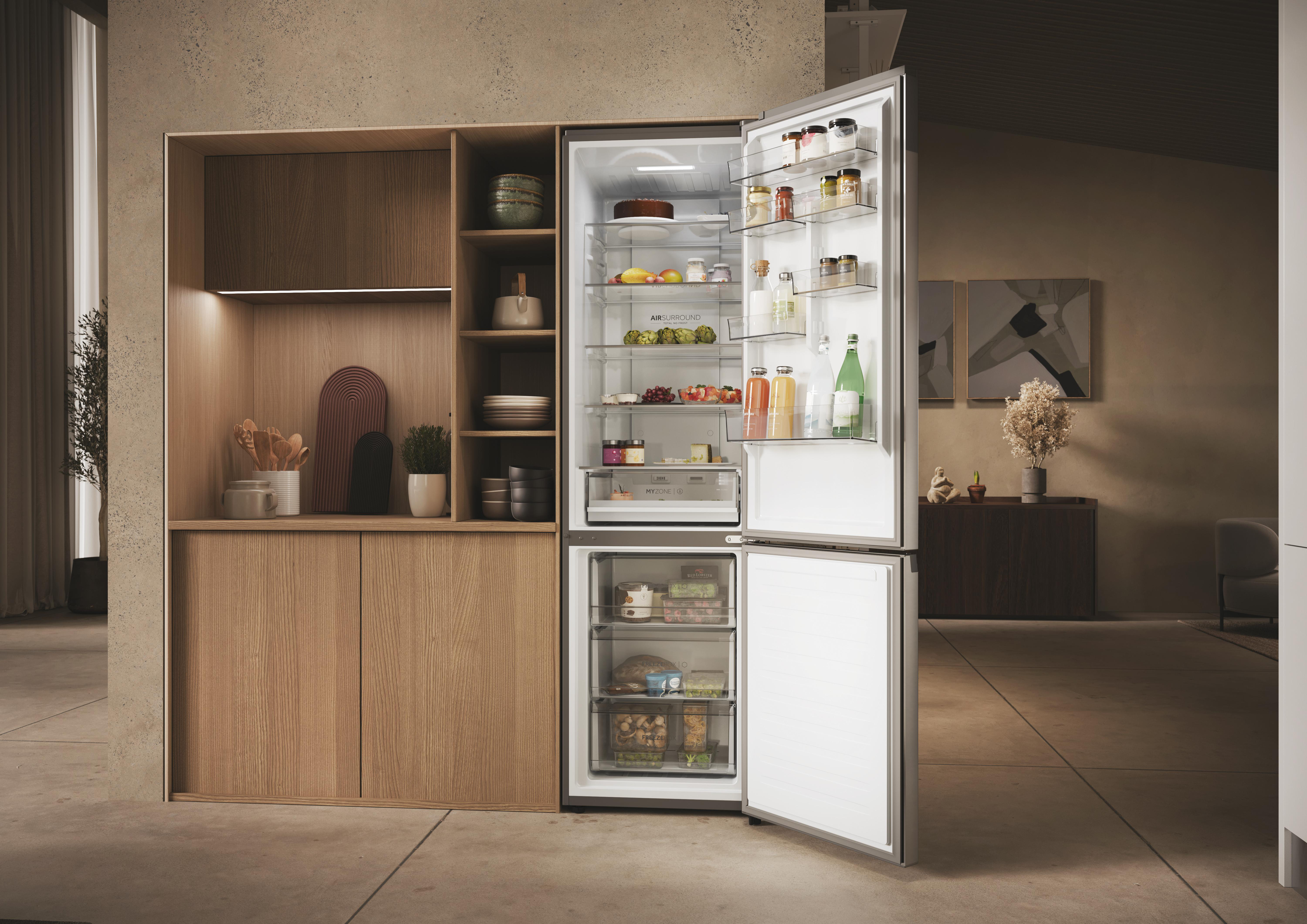 Offener Kühlschrank mit vollen Regalen in einer modernen Küche mit Holz und Stein.