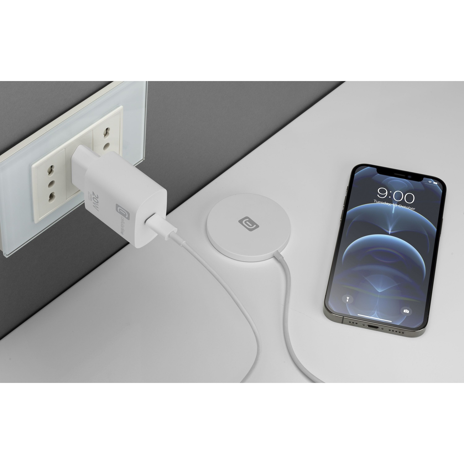 Un caricabatterie collegato a una presa. Un caricabatterie wireless e un telefono sono accanto. Il telefono mostra le 9:00.