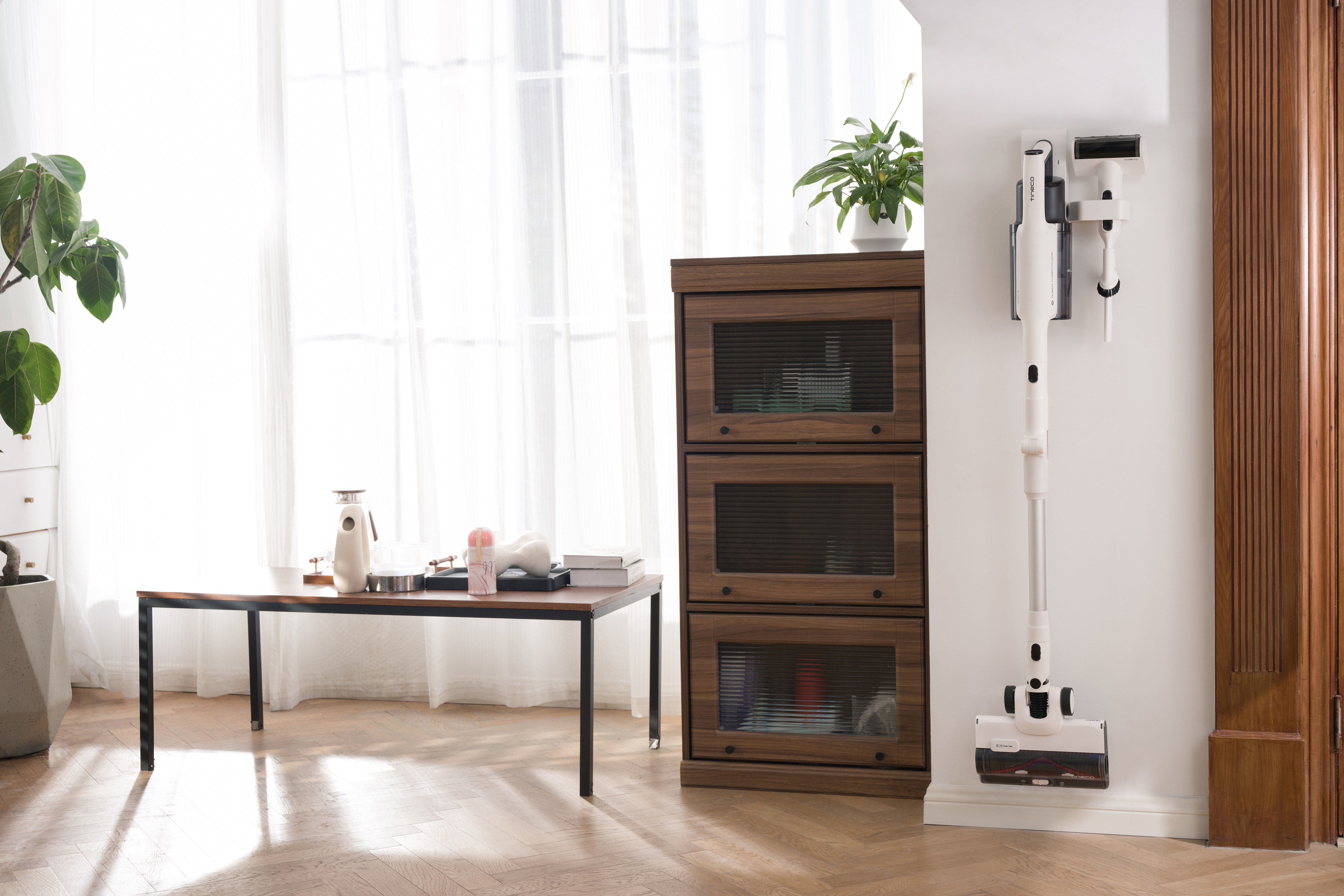 Zimmer mit Staubsauger an der Wand, Tisch und Schrank.