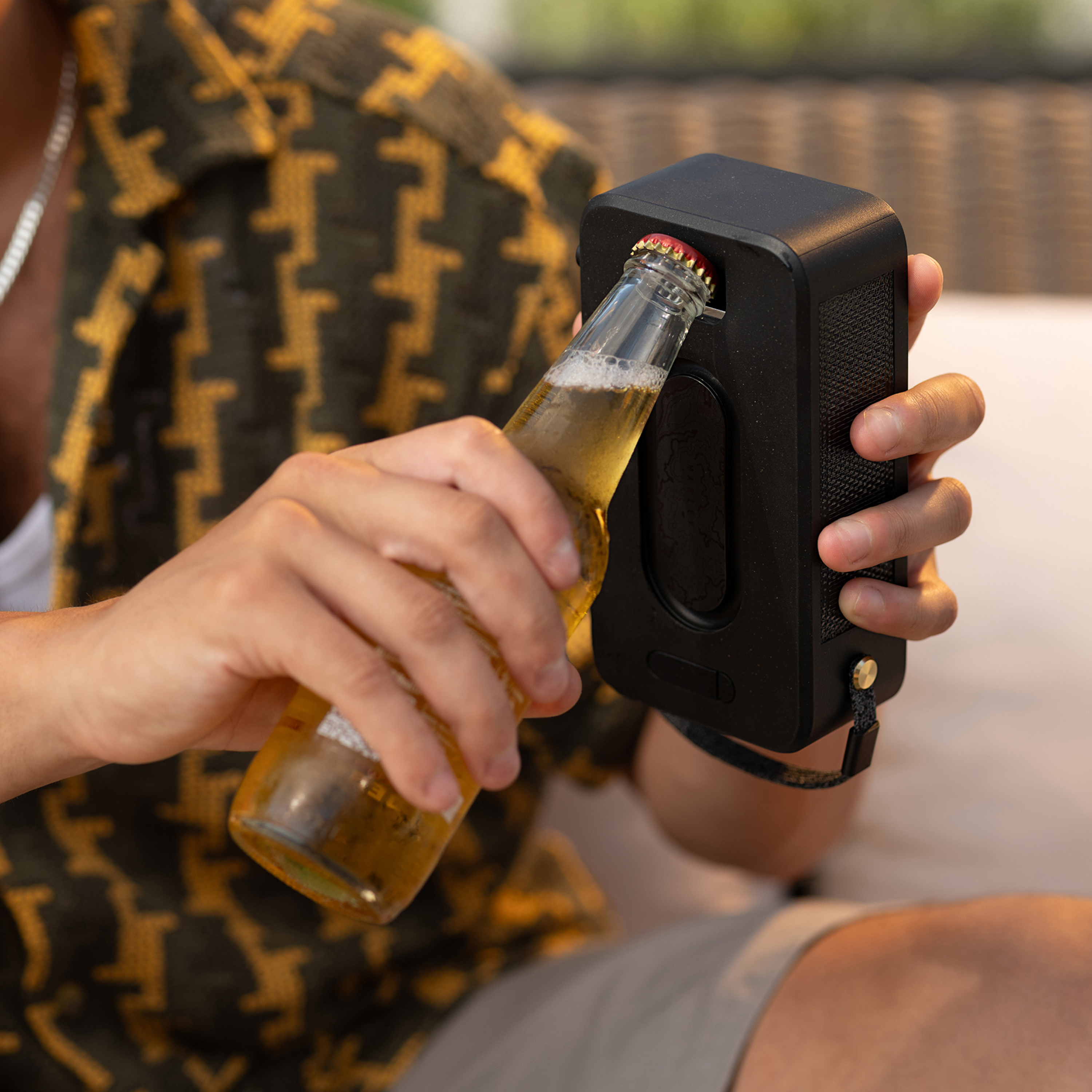 Personne ouvrant une bouteille de bière avec un ouvre-bouteille fixé à un haut-parleur.