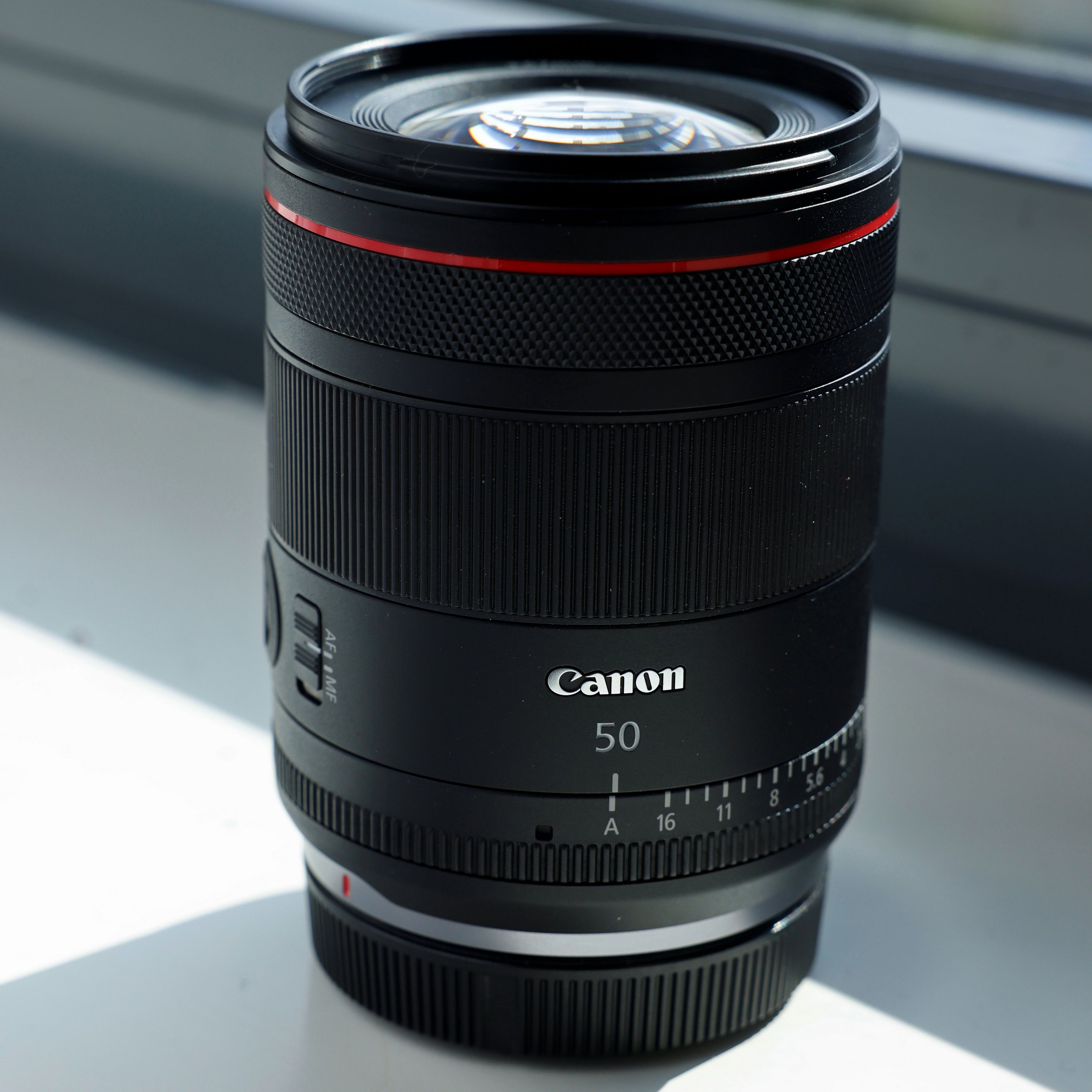 Objectif Canon noir avec détails rouges. L'objectif est sur un rebord de fenêtre.