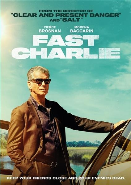 Affiche du film 'Fast Charlie' avec Pierce Brosnan. Il se tient près d'une voiture, avec un ciel bleu et de l'eau en arrière-plan.