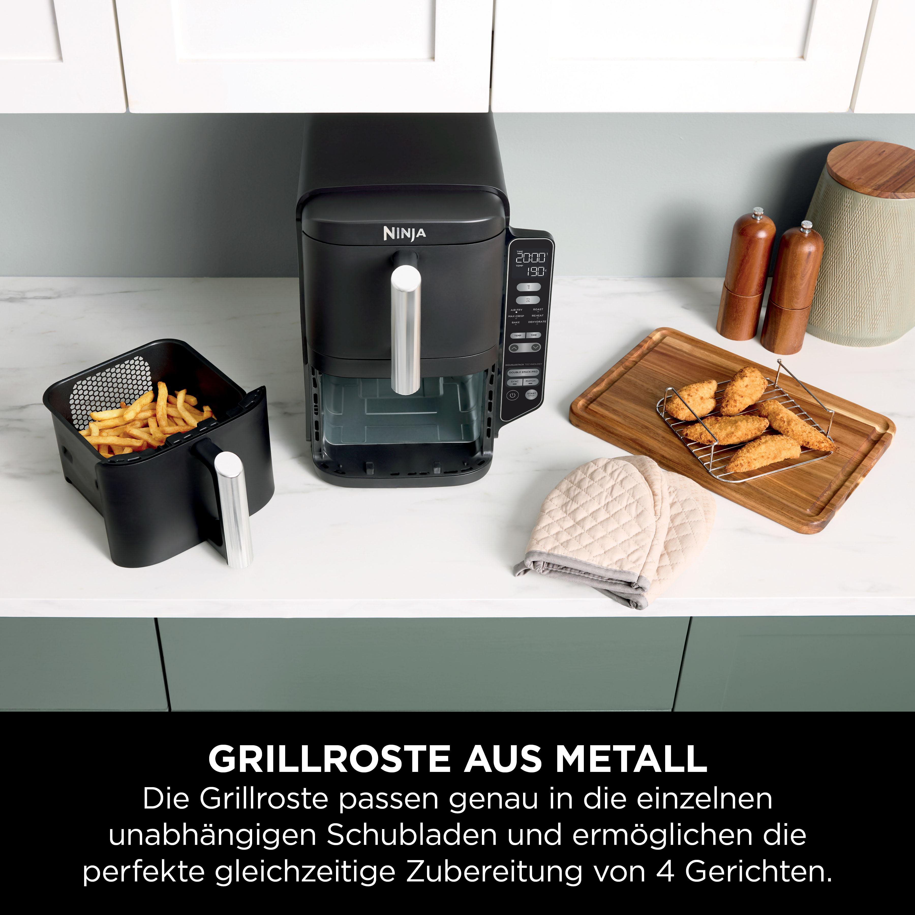 Schwarze Heißluftfritteuse mit Pommes und Hähnchenstreifen, auf einer weißen Theke.