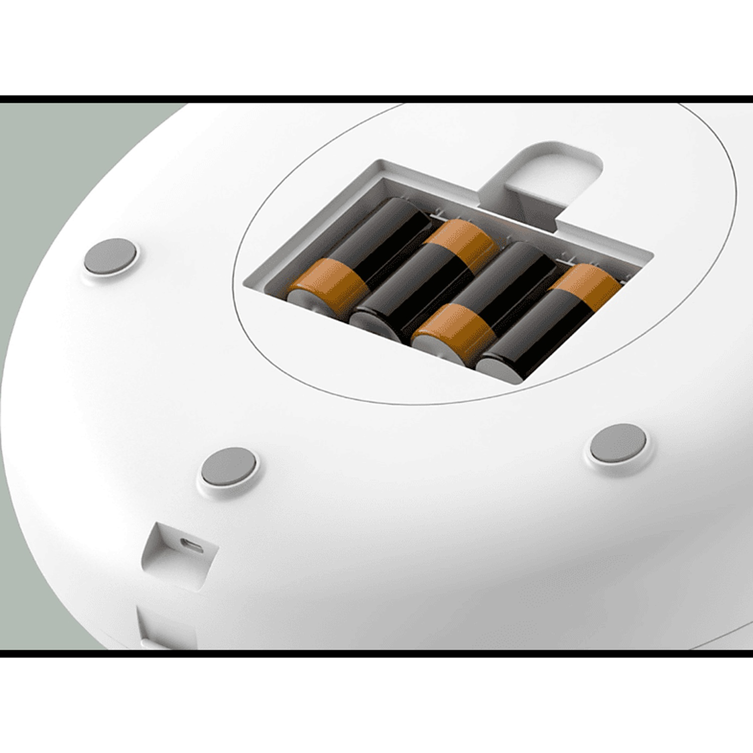 Un primo piano della parte inferiore di un dispositivo bianco che mostra un vano con quattro batterie.