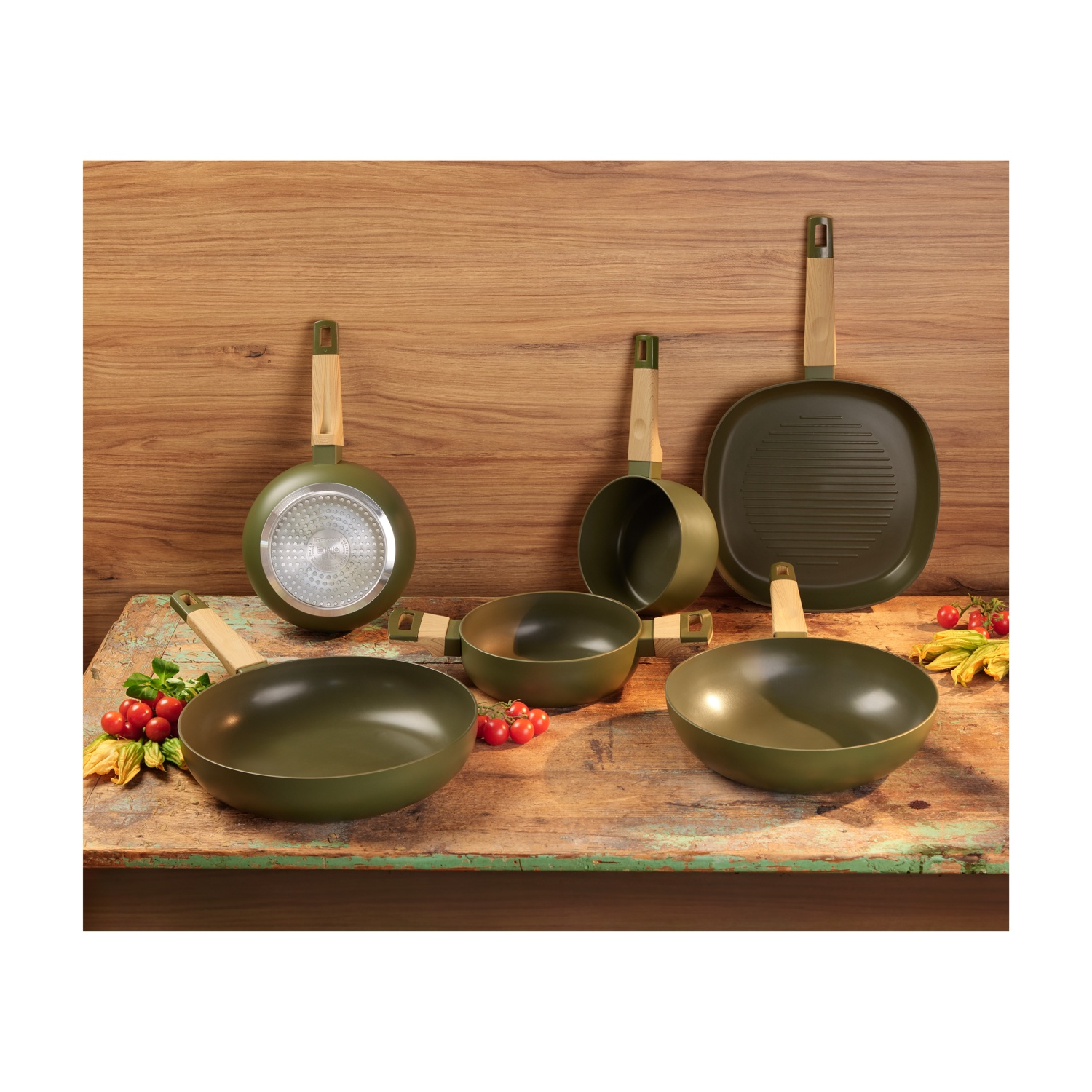 Set di utensili da cucina. Include padelle, pentole e una piastra per griglia, il tutto in verde con manici in legno.
