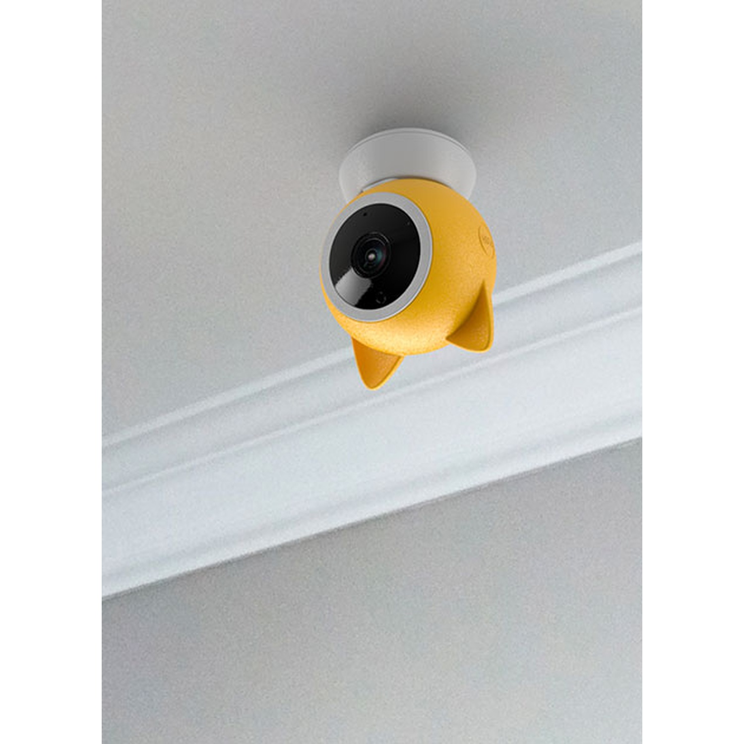 Telecamera per baby monitor gialla attaccata a un soffitto bianco. Obiettivo nero.
