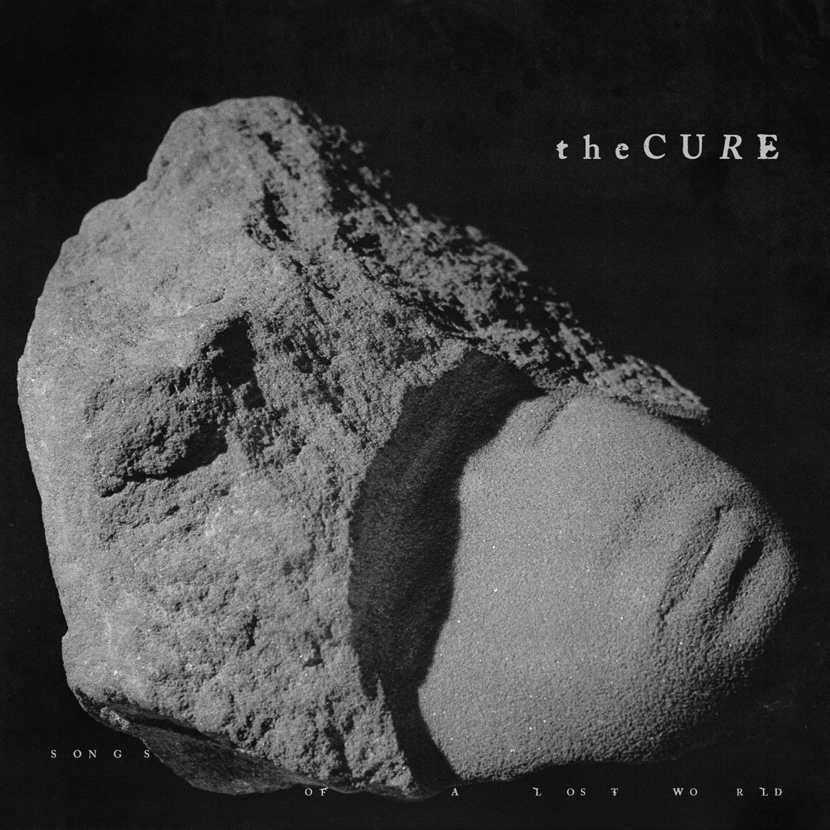 Pochette de l'album 'Songs of a Lost World' de The Cure. Elle présente un rocher gris sur fond noir.