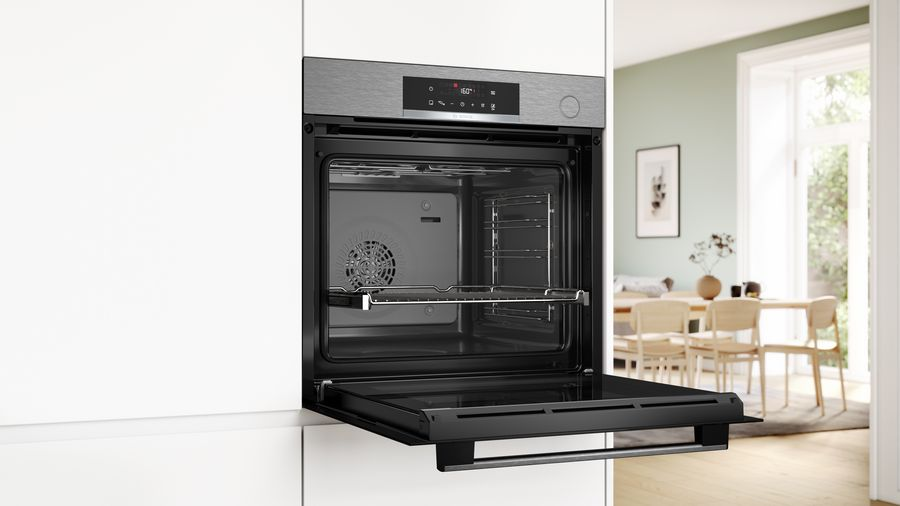 Un horno abierto integrado en un armario blanco, mostrando el interior con estantes.
