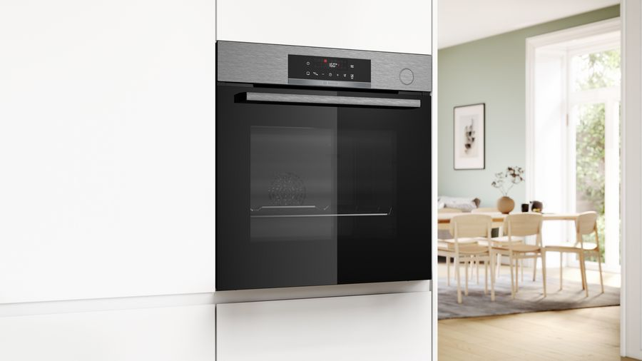 Horno empotrado en cocina blanca con comedor visible al fondo.