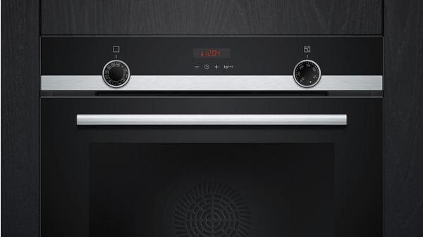 Un panel de control del horno con dos diales, un reloj digital y un asa.