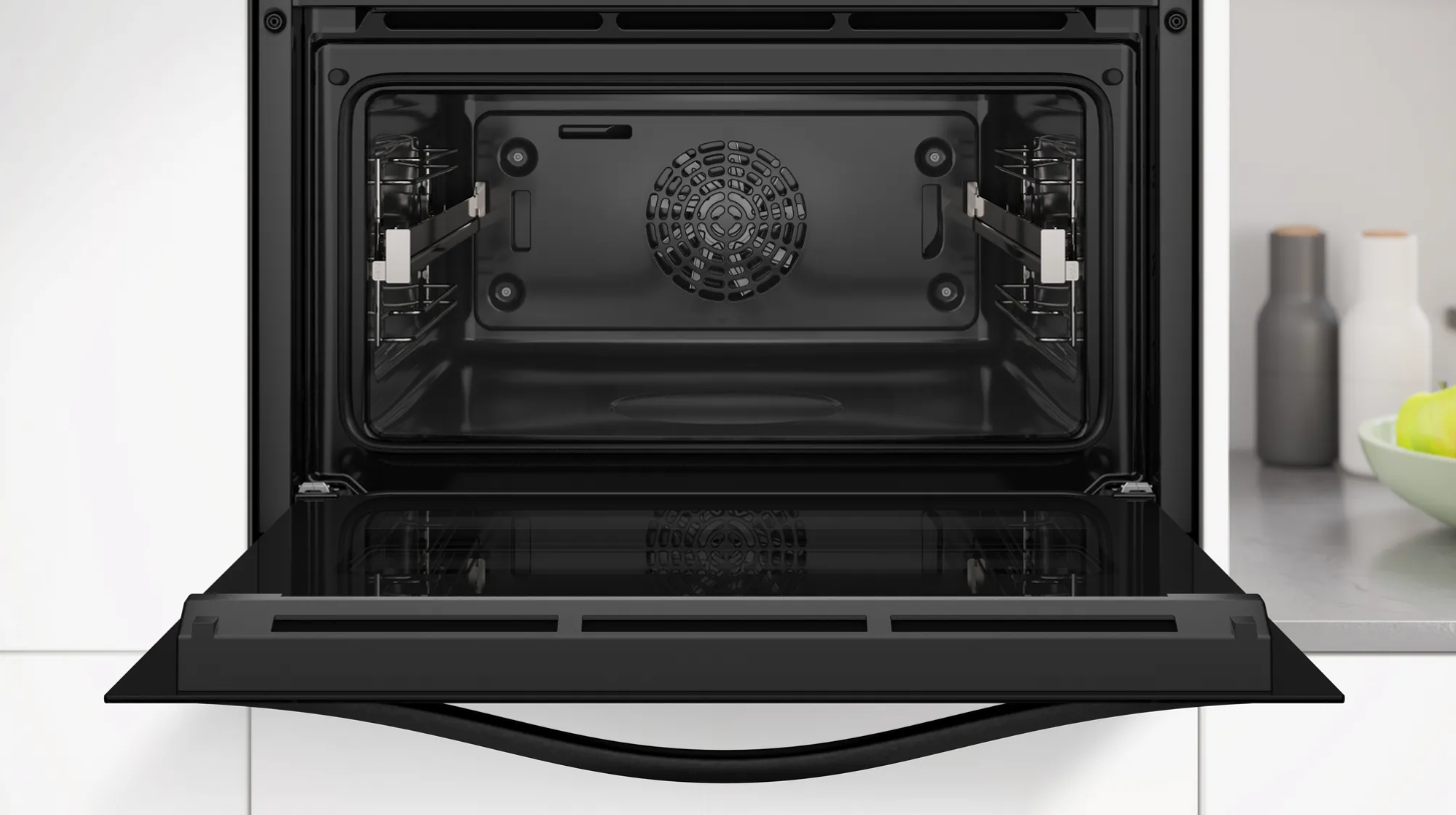 Primer plano de un horno abierto. Interior con rejillas y ventilador, puerta negra abierta.