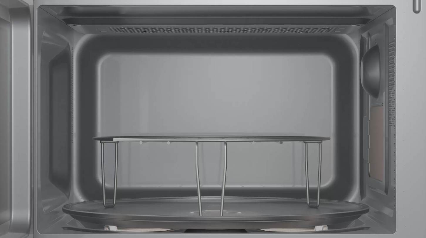 Interior de un horno microondas, con bandeja de vidrio y rejilla metálica, color plateado.