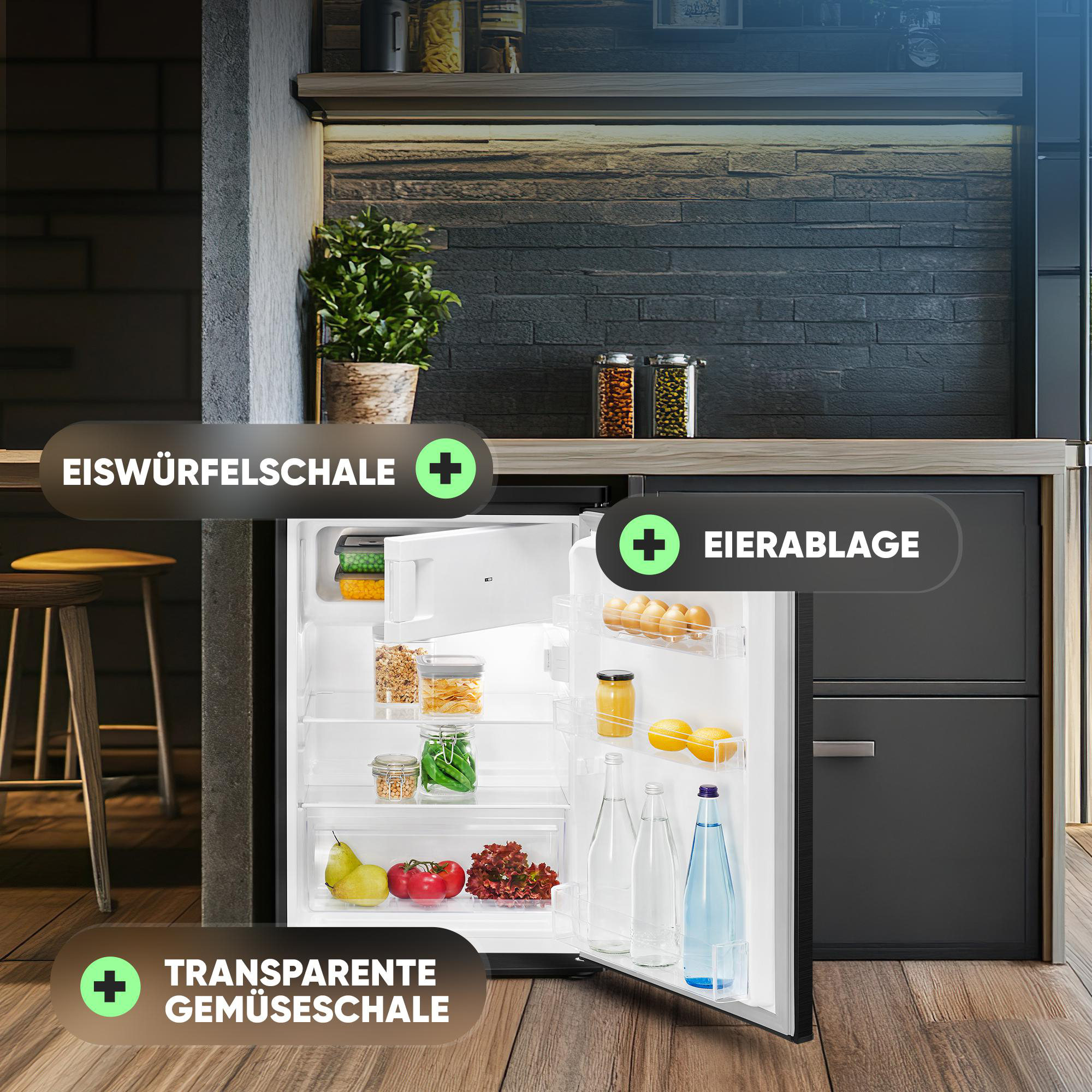 Ein offener Mini-Kühlschrank zeigt Lebensmittel wie Obst, Gemüse und Gläser. Eine Pflanze steht in der Nähe. Der Kühlschrank ist in einer Küche.
