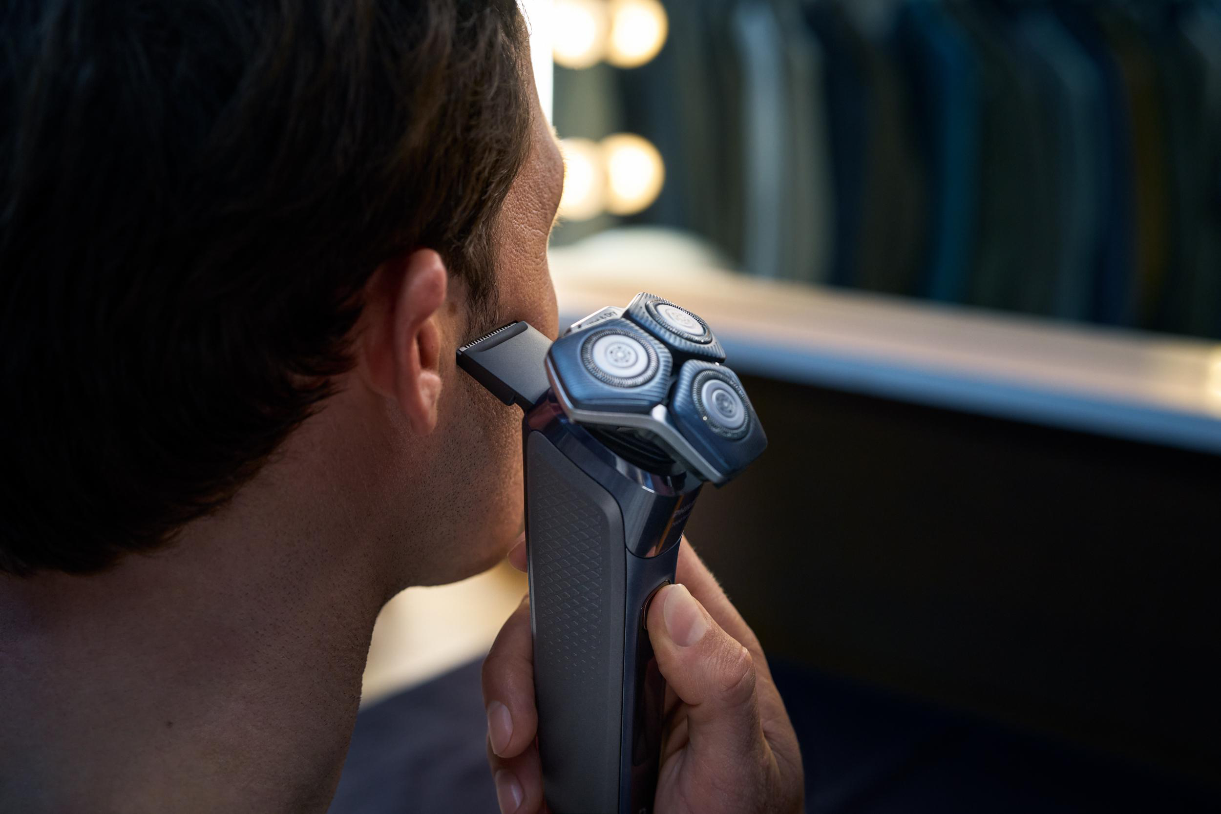 Mann rasiert sich mit einem grauen Elektrorasierer, Nahaufnahme.