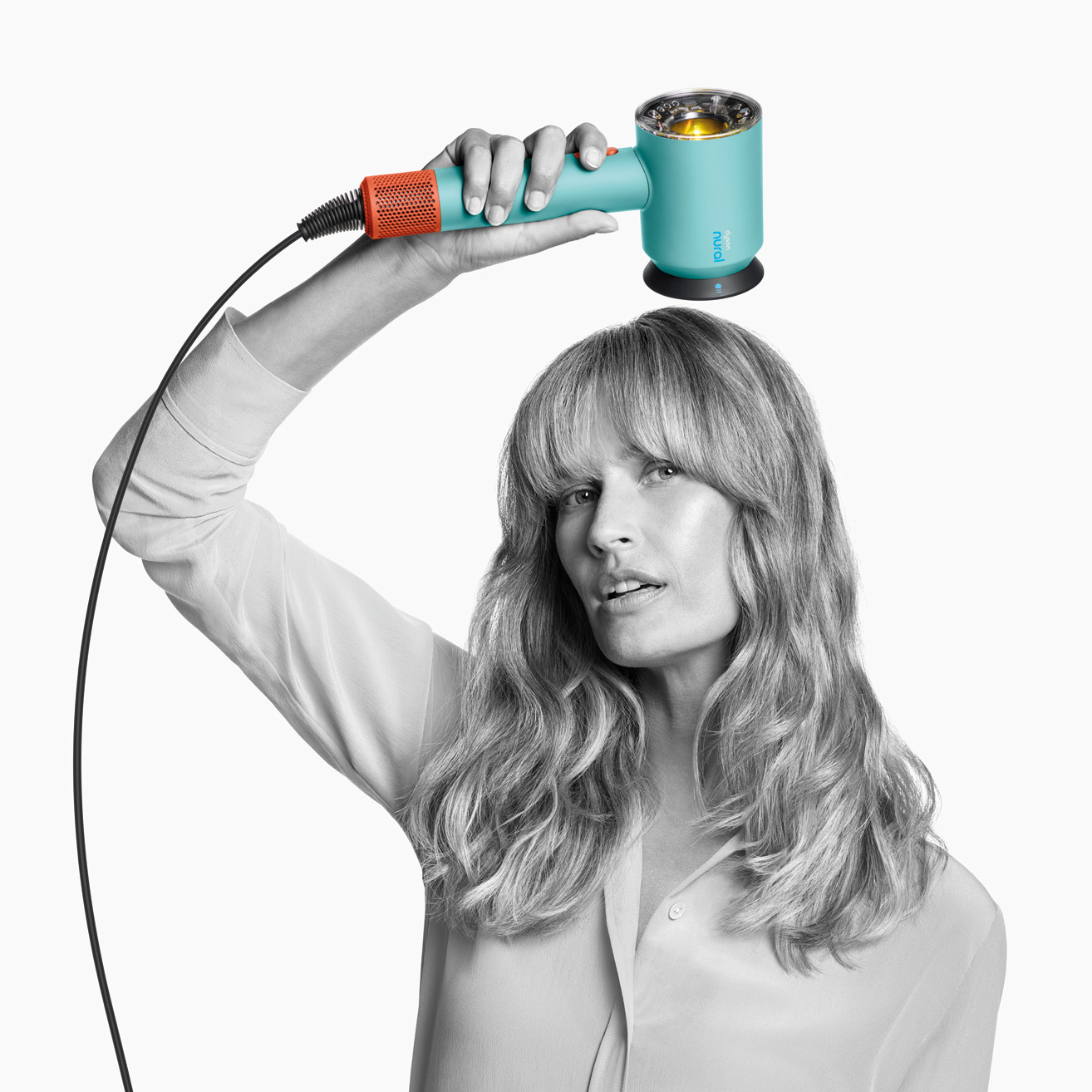 Kobieta trzymająca turkusową i pomarańczową suszarkę do włosów nad głową.