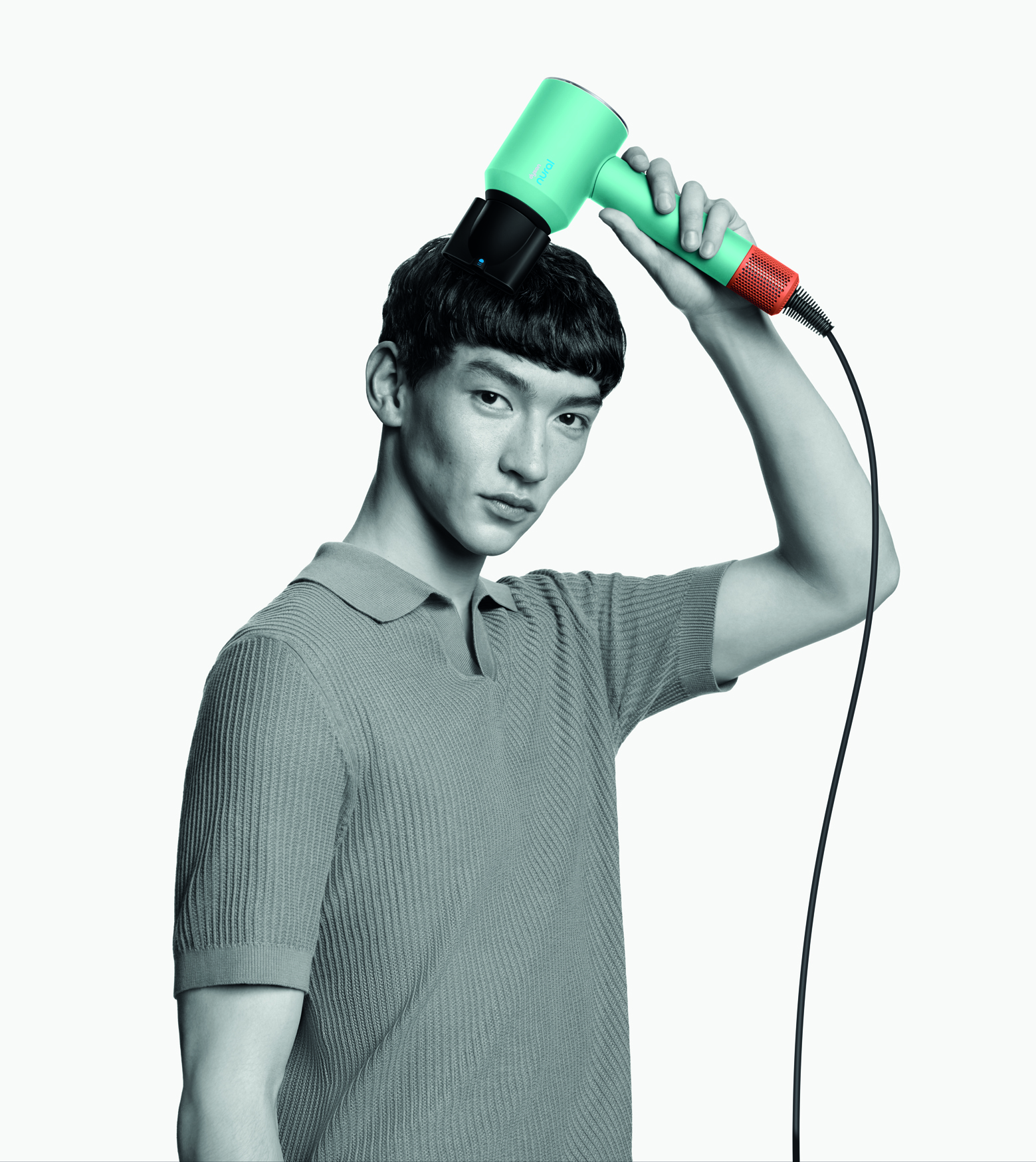 Mężczyzna używający turkusowo-pomarańczowej suszarki do włosów na głowie.