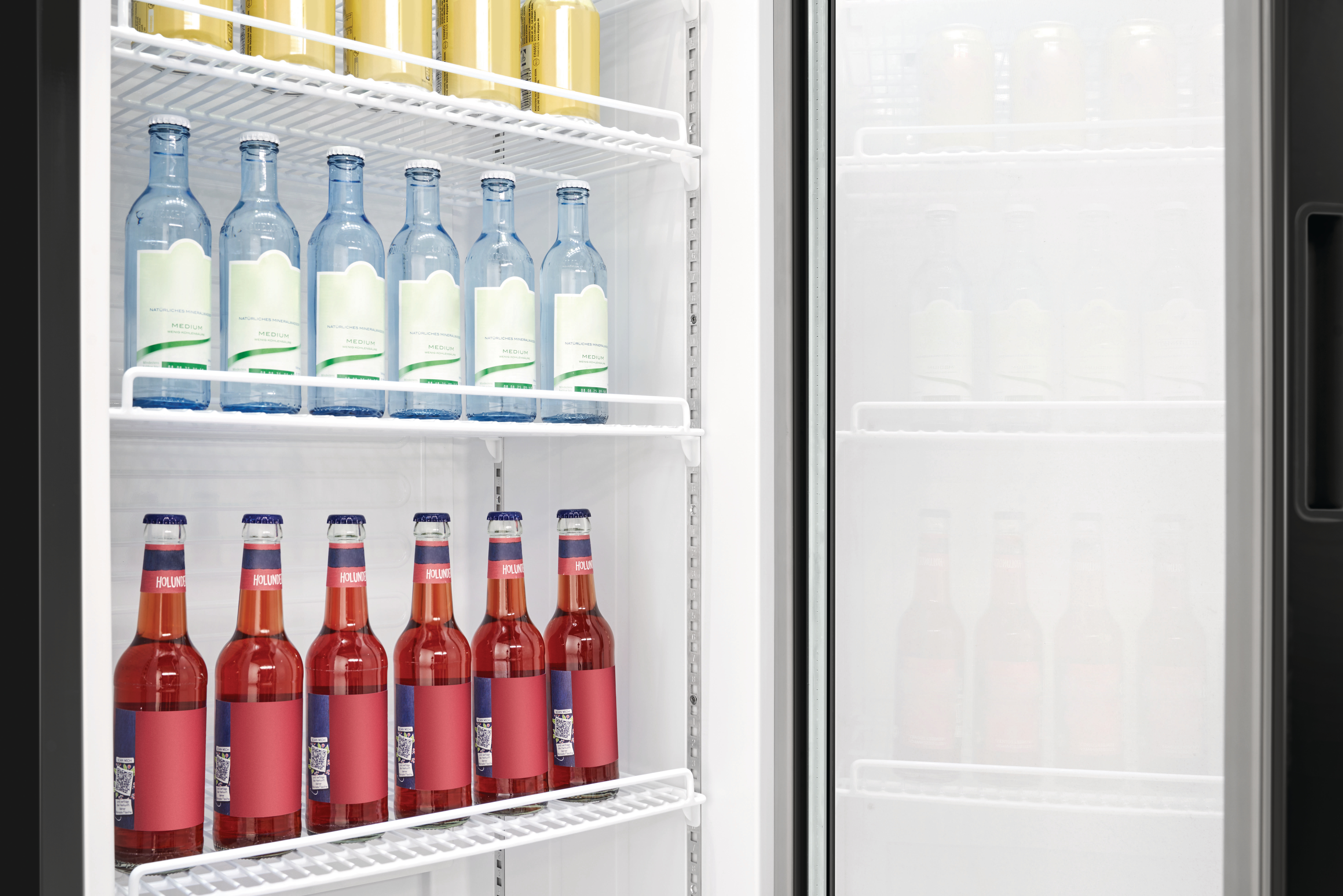 Ein Kühlschrank mit Glasflaschen Wasser und Bier. Die Tür ist offen.