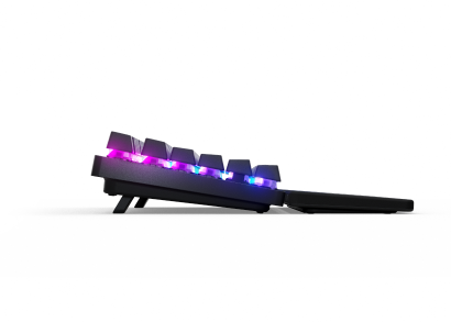 Egy fekete billentyűzet RGB-fényekkel, amelyek átsütnek a billentyűkön, fekete háttér előtt.