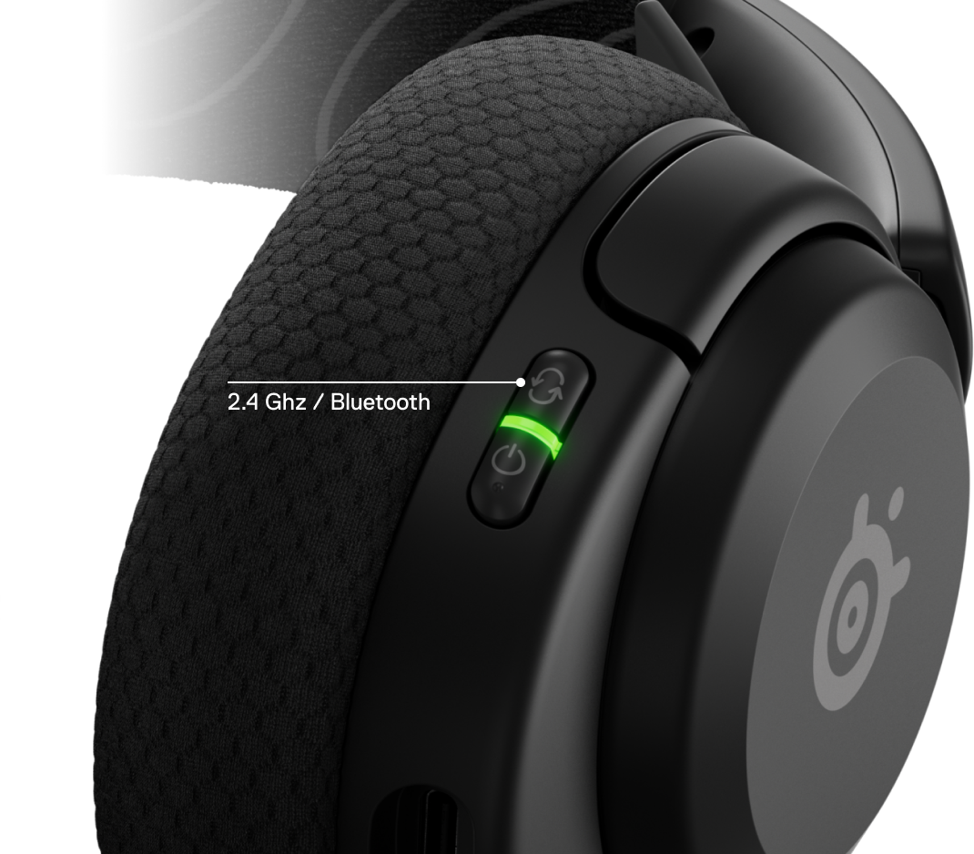 Fekete fejhallgató részlete, zölden világító bekapcsológombbal és a SteelSeries logóval.