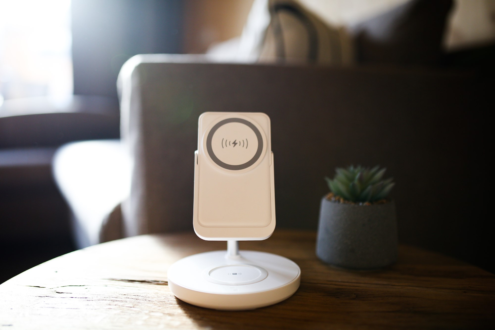 Biała bezprzewodowa podstawka ładująca z telefonem i małą rośliną.