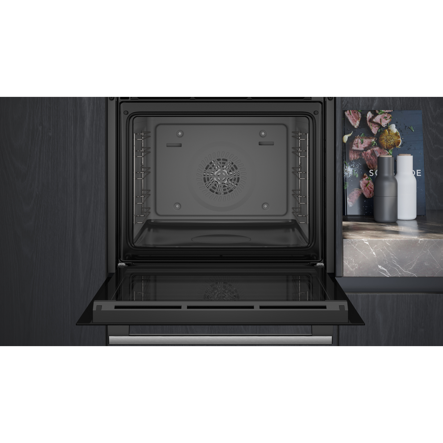 An open oven interior, showing the inside cavity, with a dark gray interior and black door.