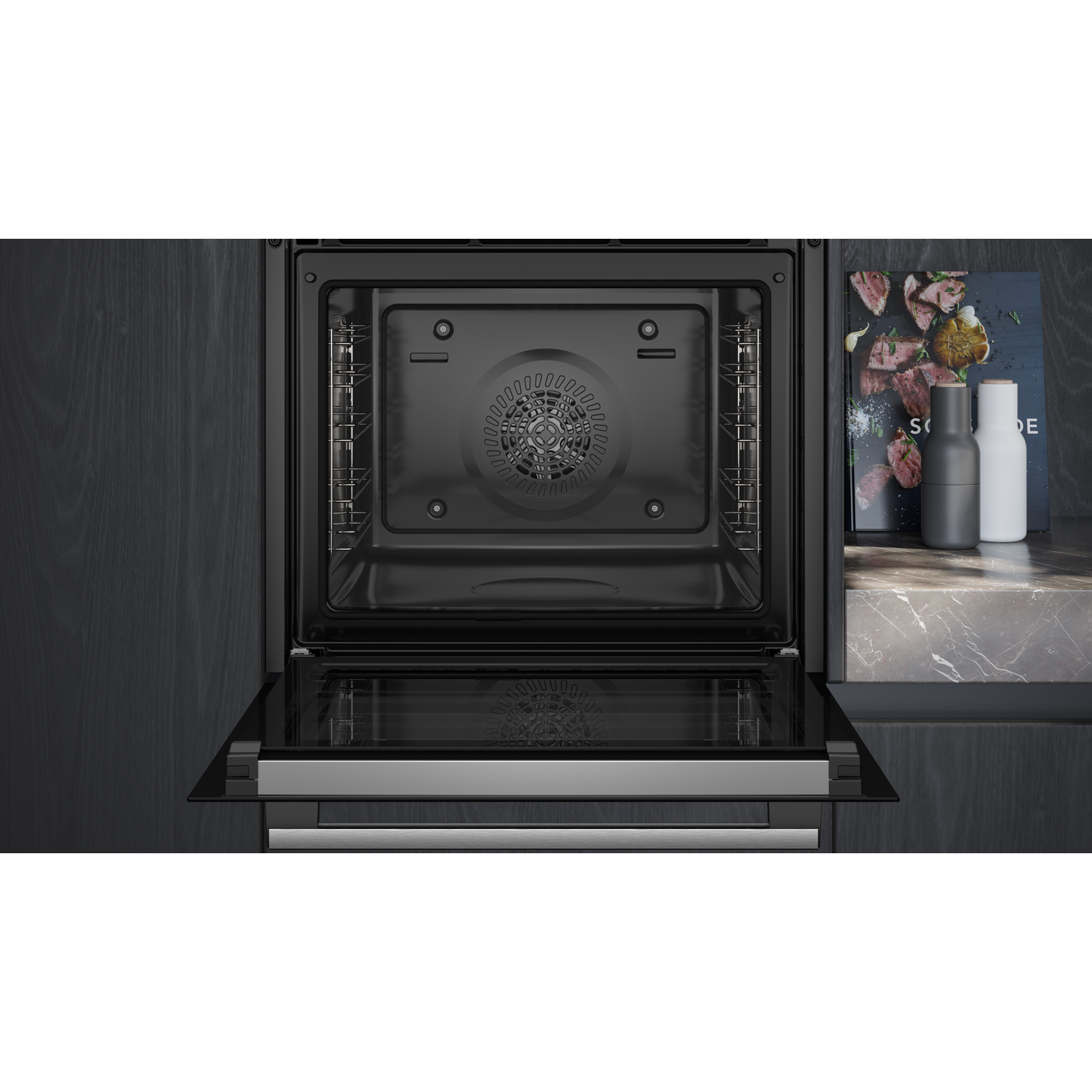 Open oven with interior visible. Dark background. Oven door open. Stainless steel interior.