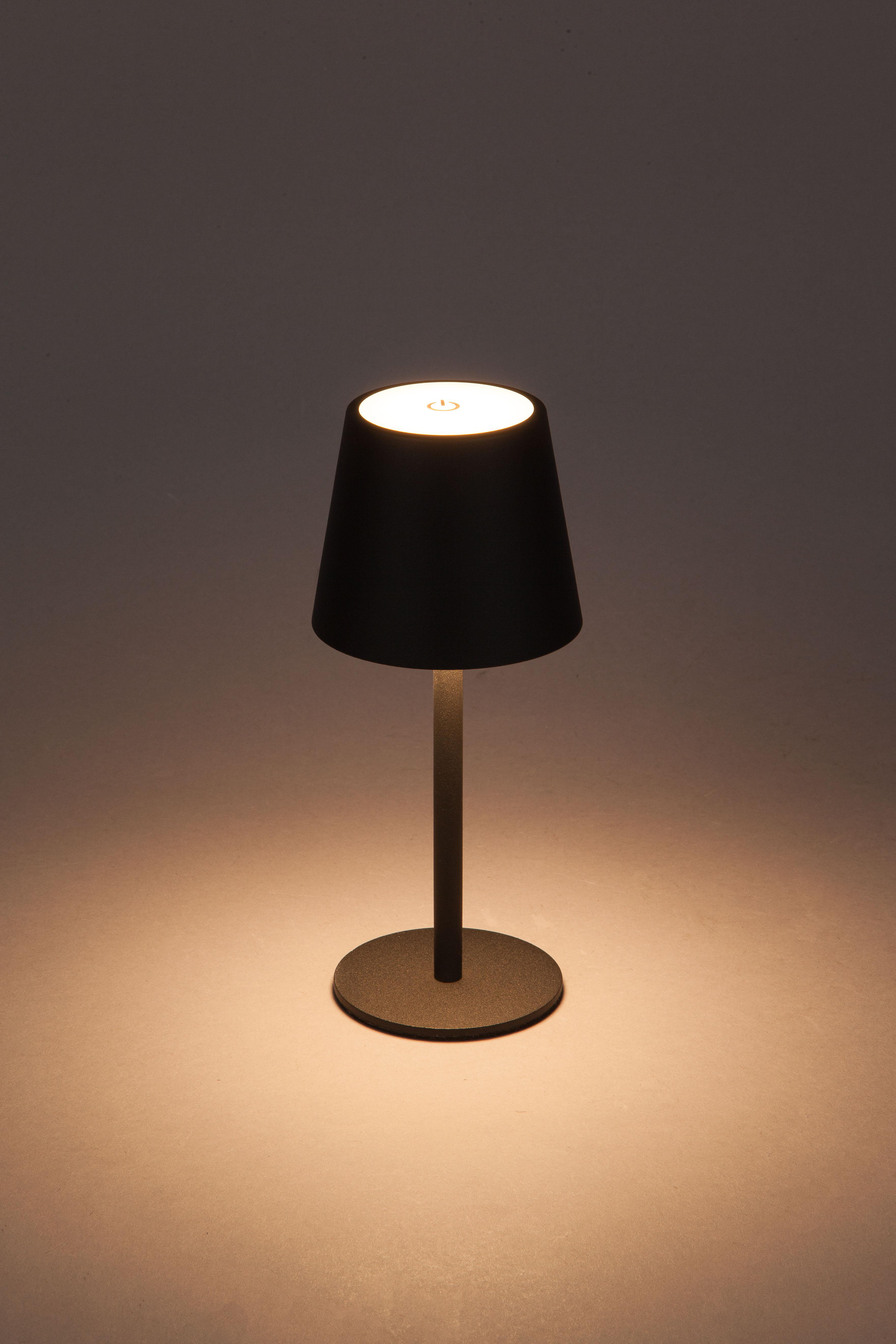 Eine schwarze Tischlampe mit rundem Sockel, beleuchtet, vor grauem Hintergrund.
