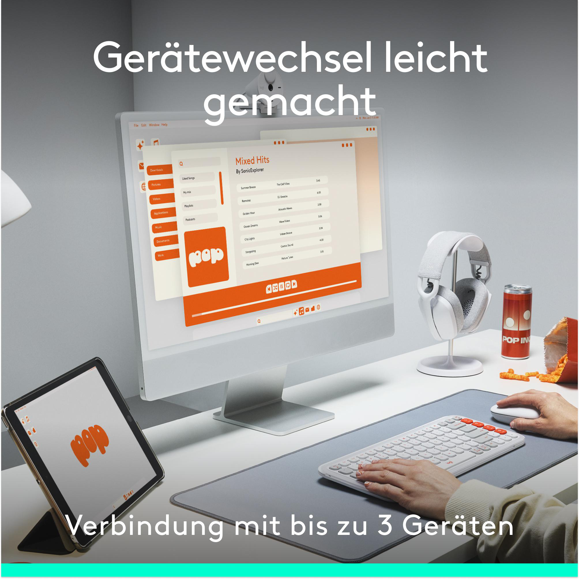 Ein Schreibtisch mit Computer, Tablet, Kopfhörern und einer Dose Pop In.