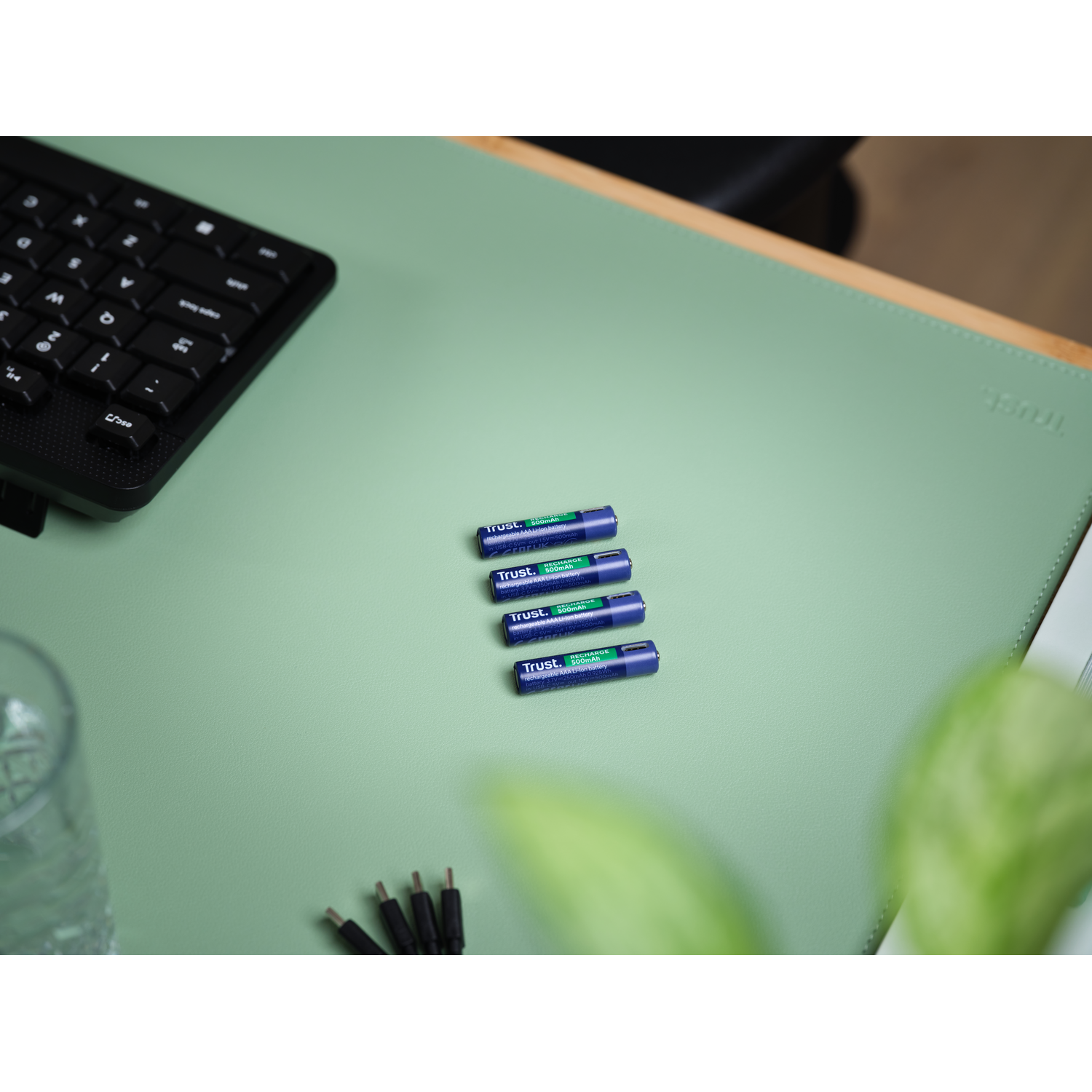 Four blue batteries on a green desk mat. 