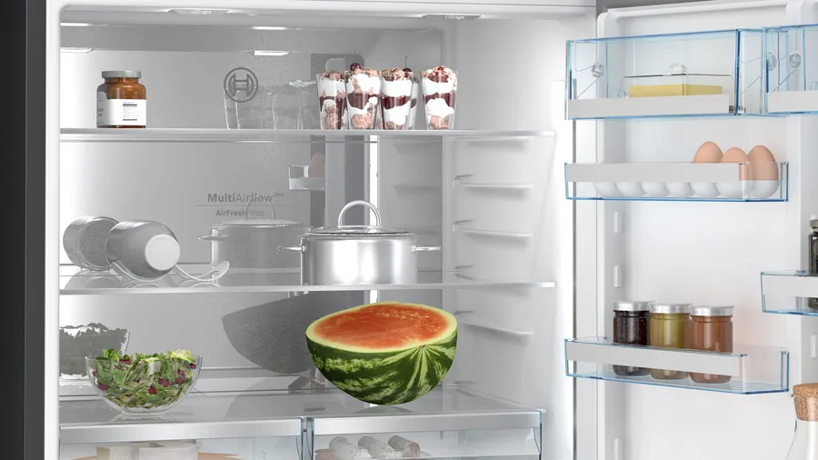 Açık buzdolabı içi. Karpuz, salata ve kavanozlar gibi yiyeceklerin bulunduğu raflar.