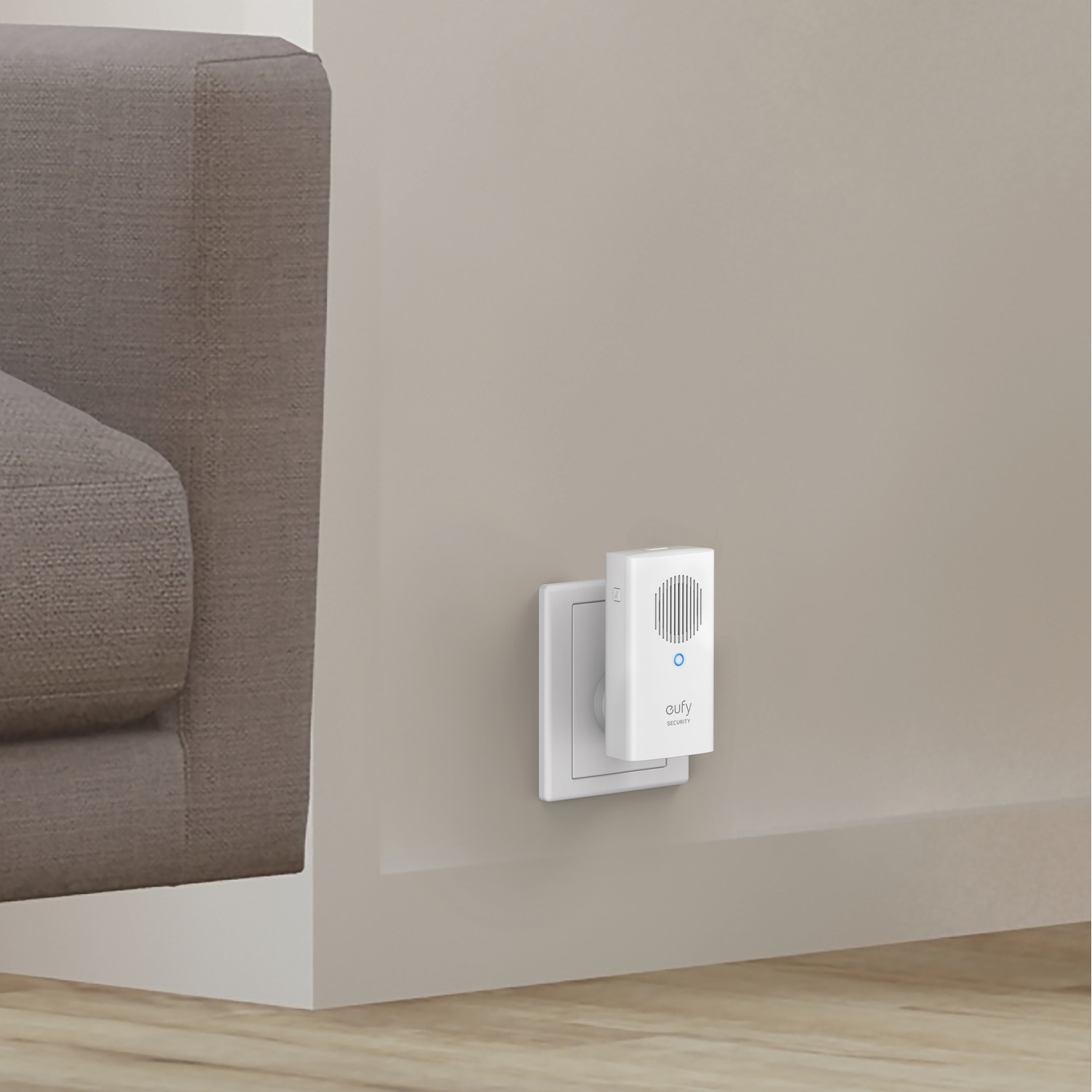Une sonnette intelligente eufy blanche avec un récepteur enfichable blanc sur un mur, près d'un canapé.