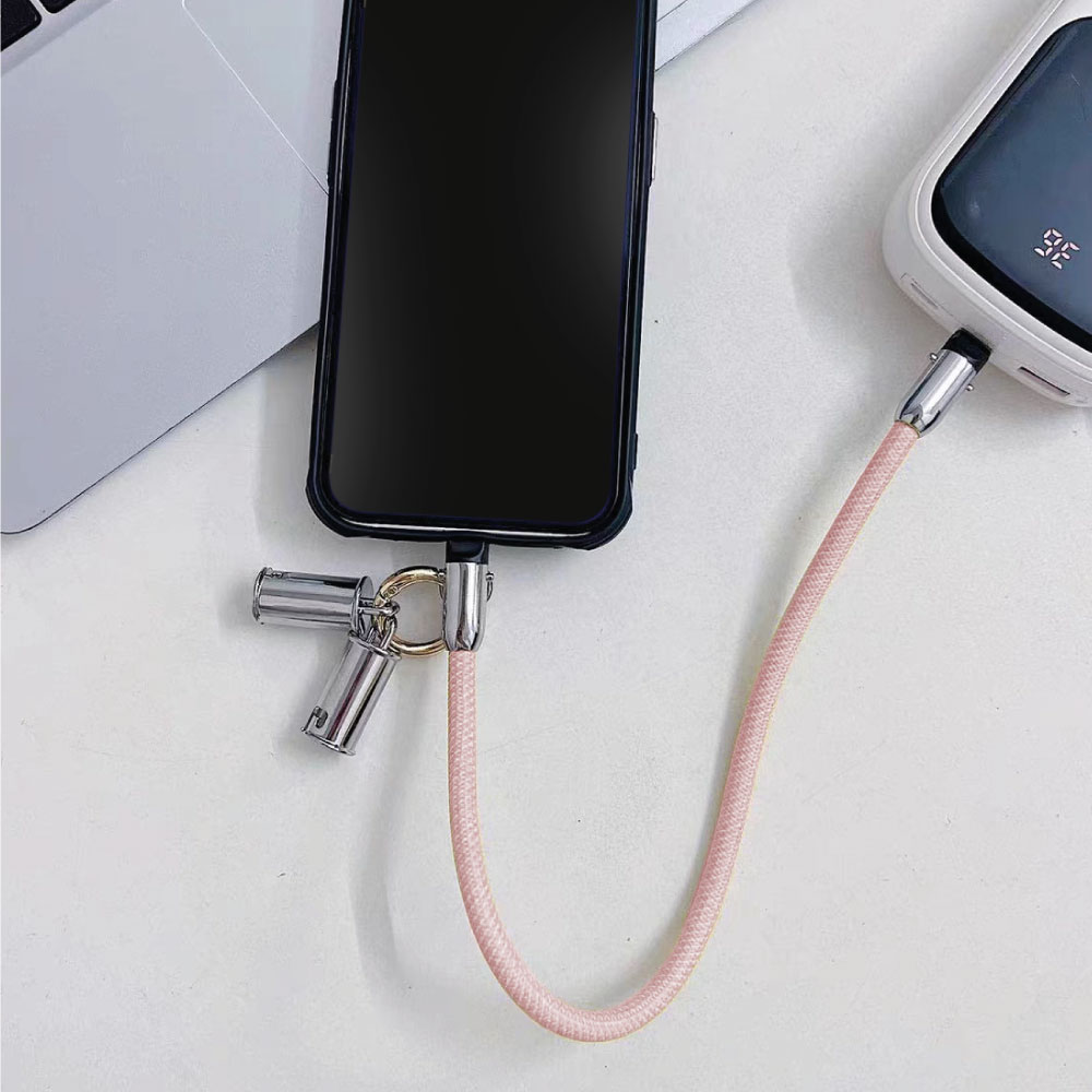 Cable de carga rosa con teléfono conectado. También hay un banco de energía conectado. Fondo blanco.