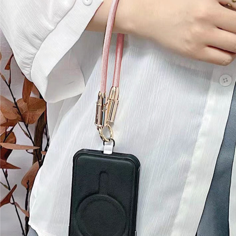 Una mano sosteniendo un teléfono negro con un cordón rosa.