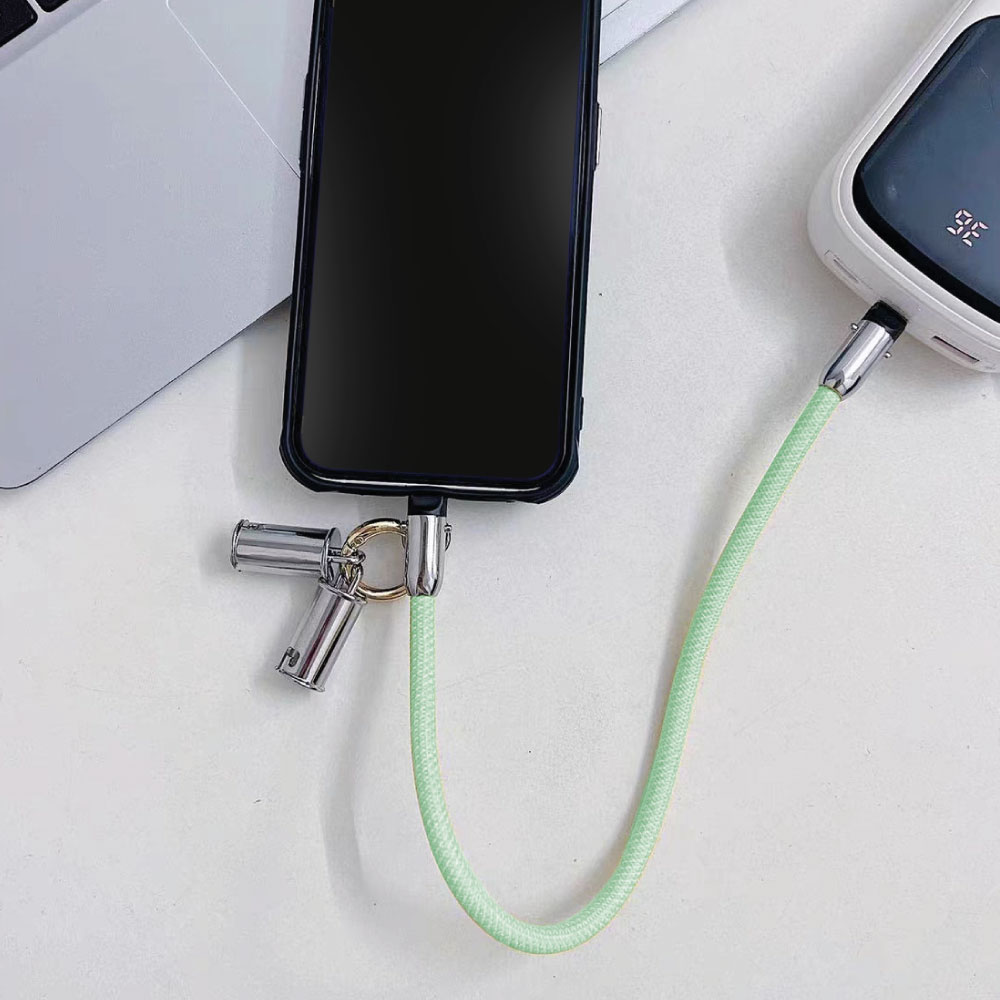 Un teléfono está conectado a un banco de energía con un cable verde.